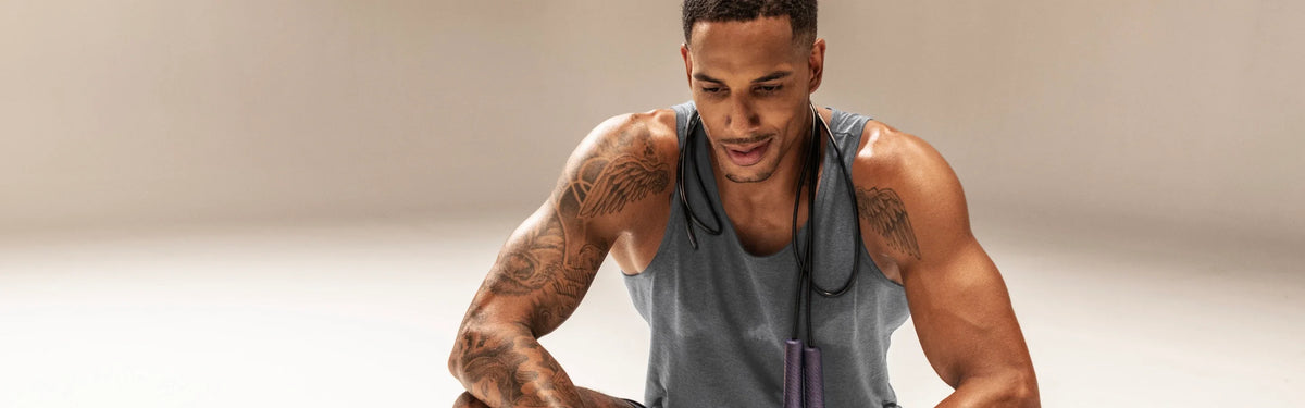 Man with a EQYP jump rope draped around his neck, pausing during a cardio conditioning workout.