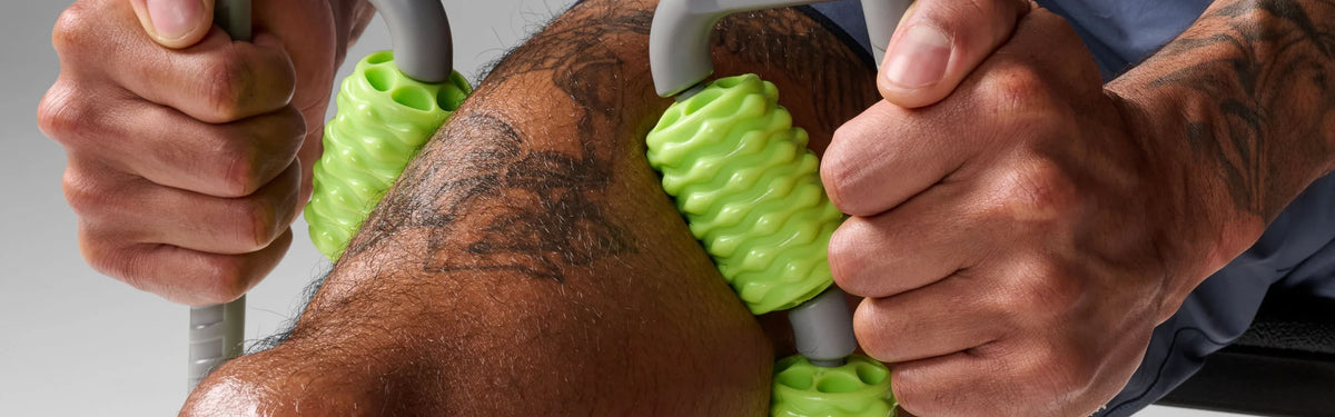 Close-up of a person using green EQYP muscle compressor rollers on the shoulder and upper arm for deep tissue massage.