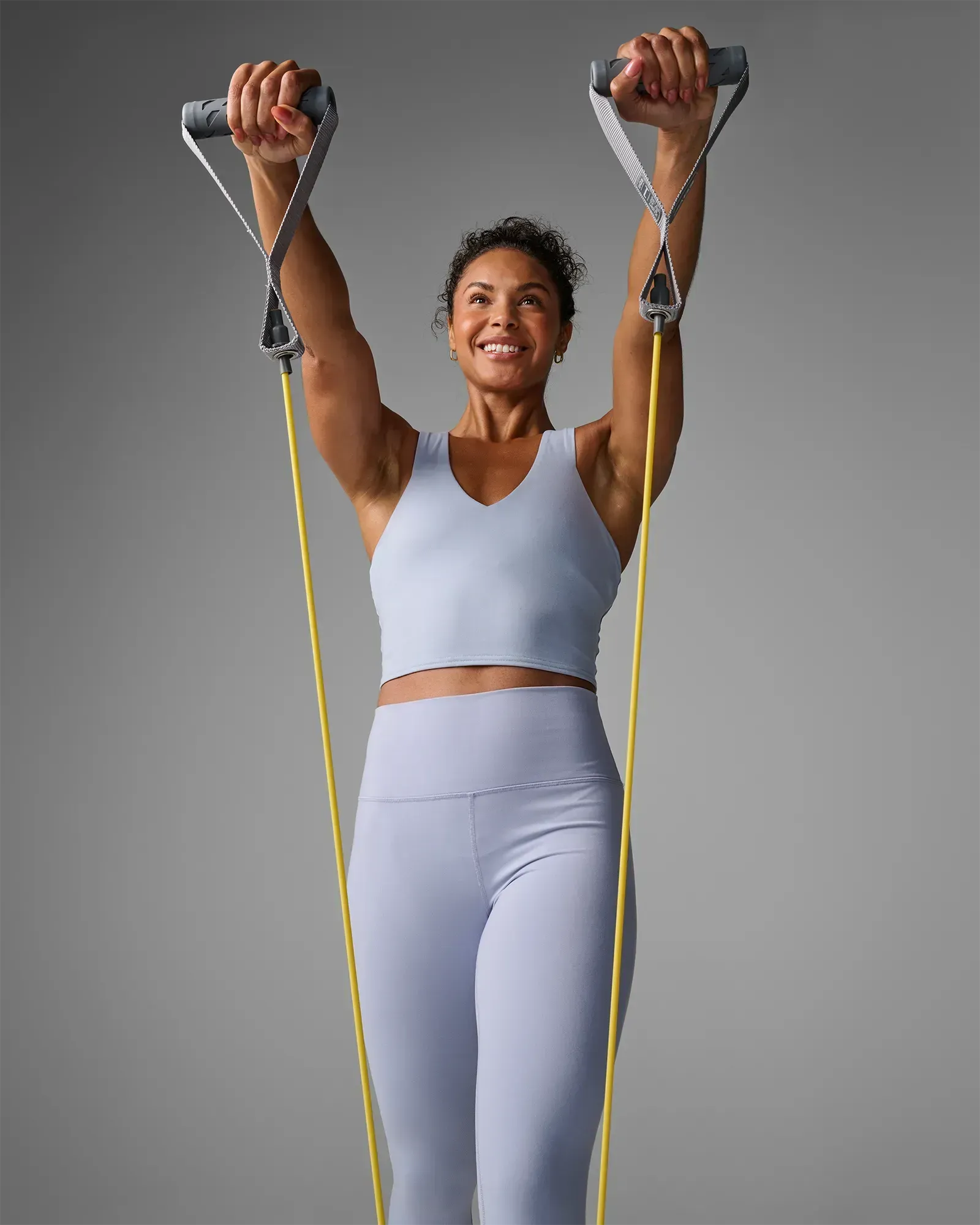 Woman performing a standing overhead pull using EQYP Power Tubes with Handles Extra Light