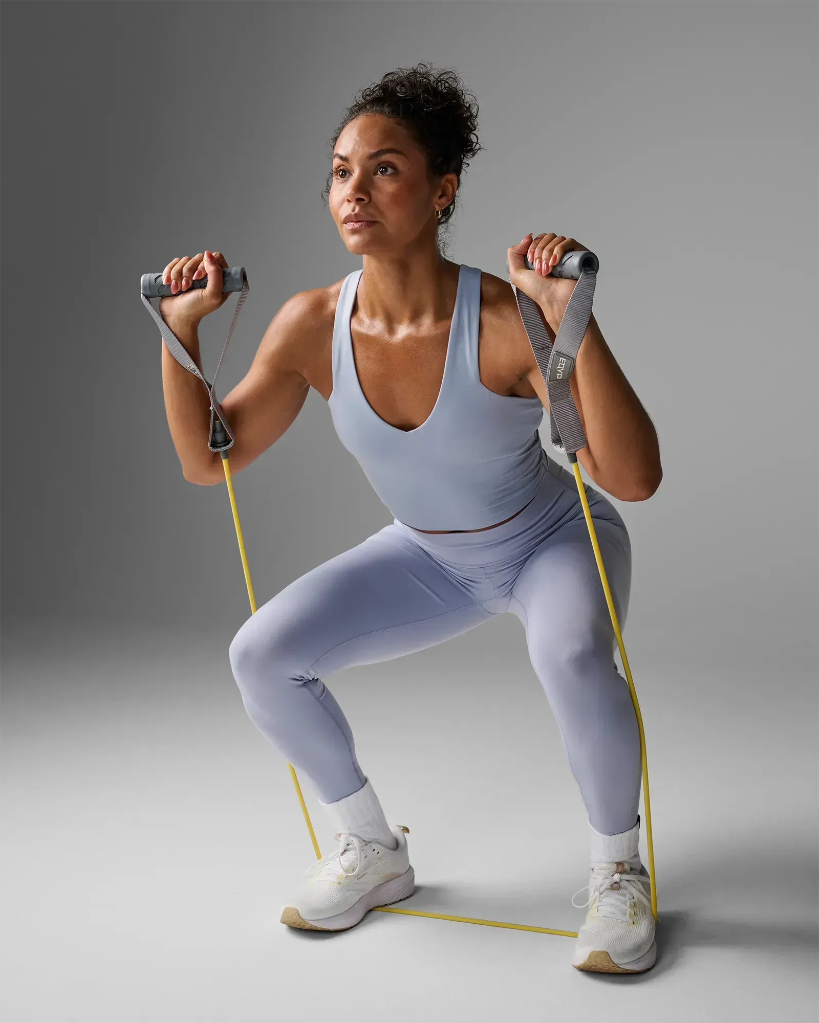 Woman performing a squat with handles at shoulder height using EQYP Power Tubes with Handles Extra Light