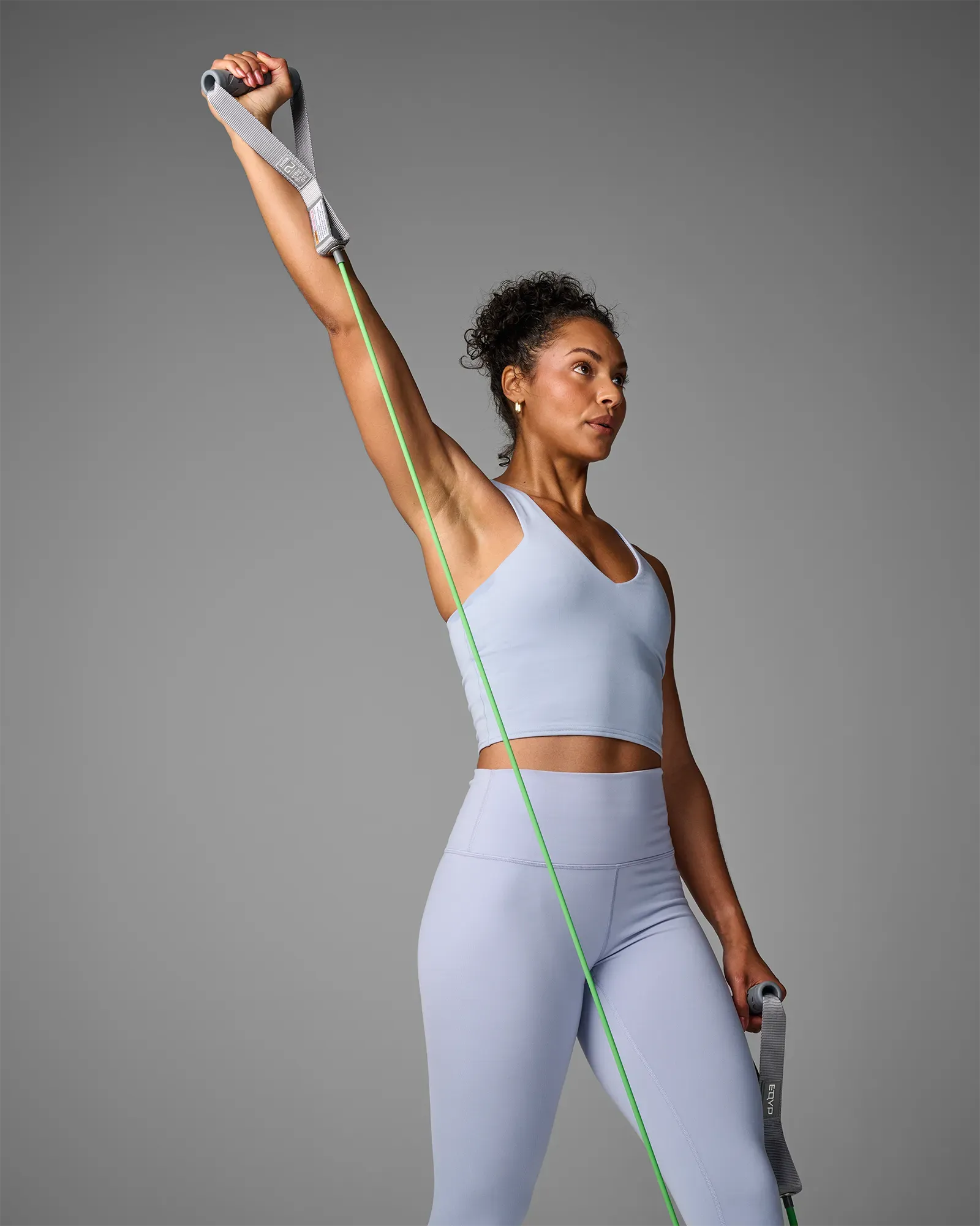 Woman performing a standing single-arm overhead press using EQYP Power Tubes with Handles Light green resistance tube