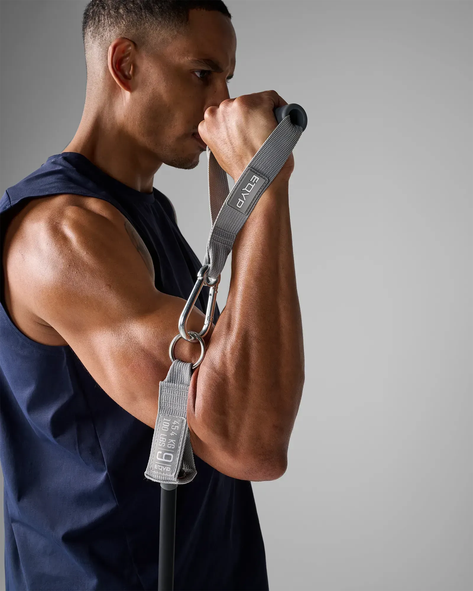 Man performing a standing single-arm curl using EQYP Power Tubes 100 lbs black resistance tube with handle, side profile view