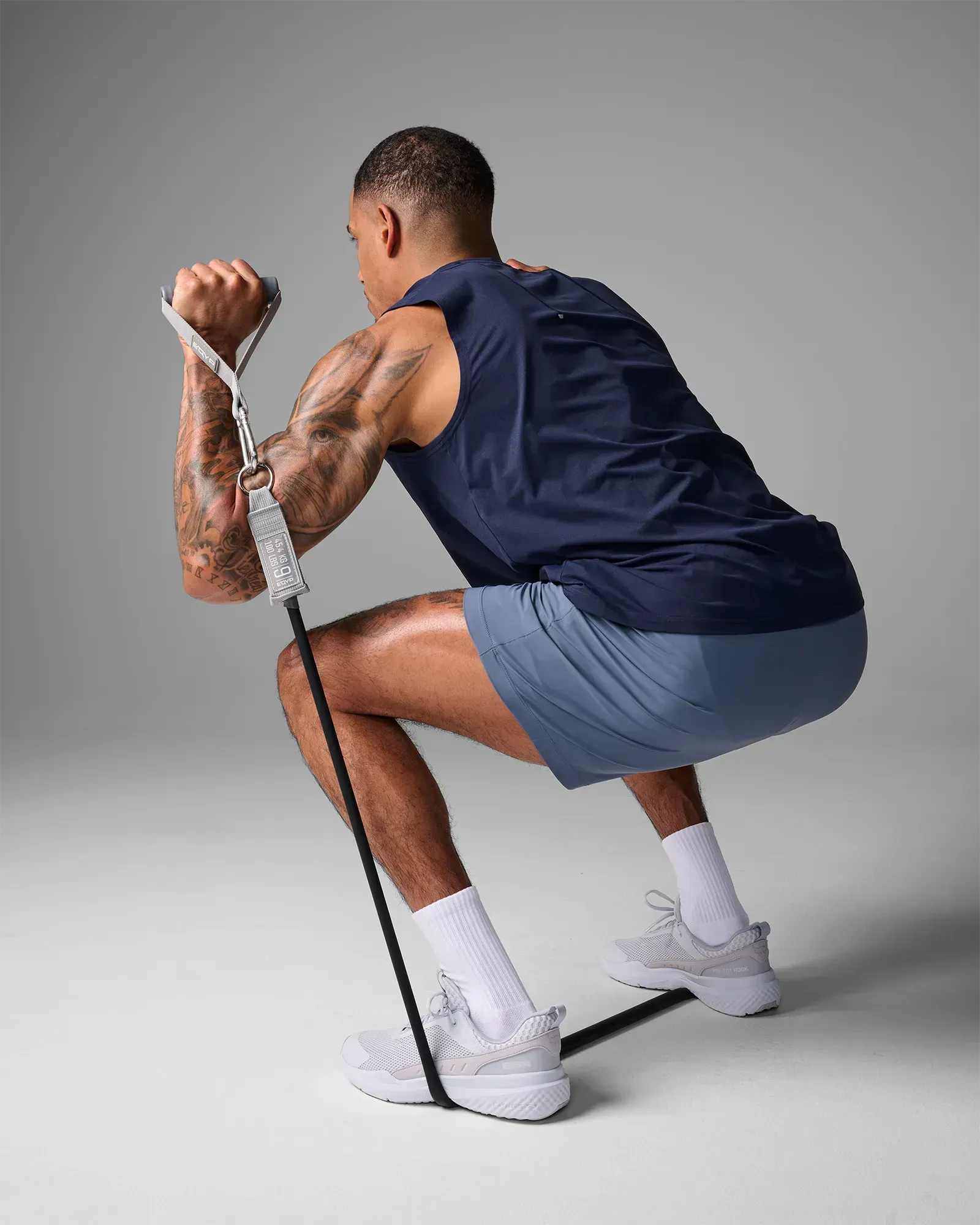Man performing a squat press using EQYP Power Tubes 100 lbs black resistance tube with handle, rear view