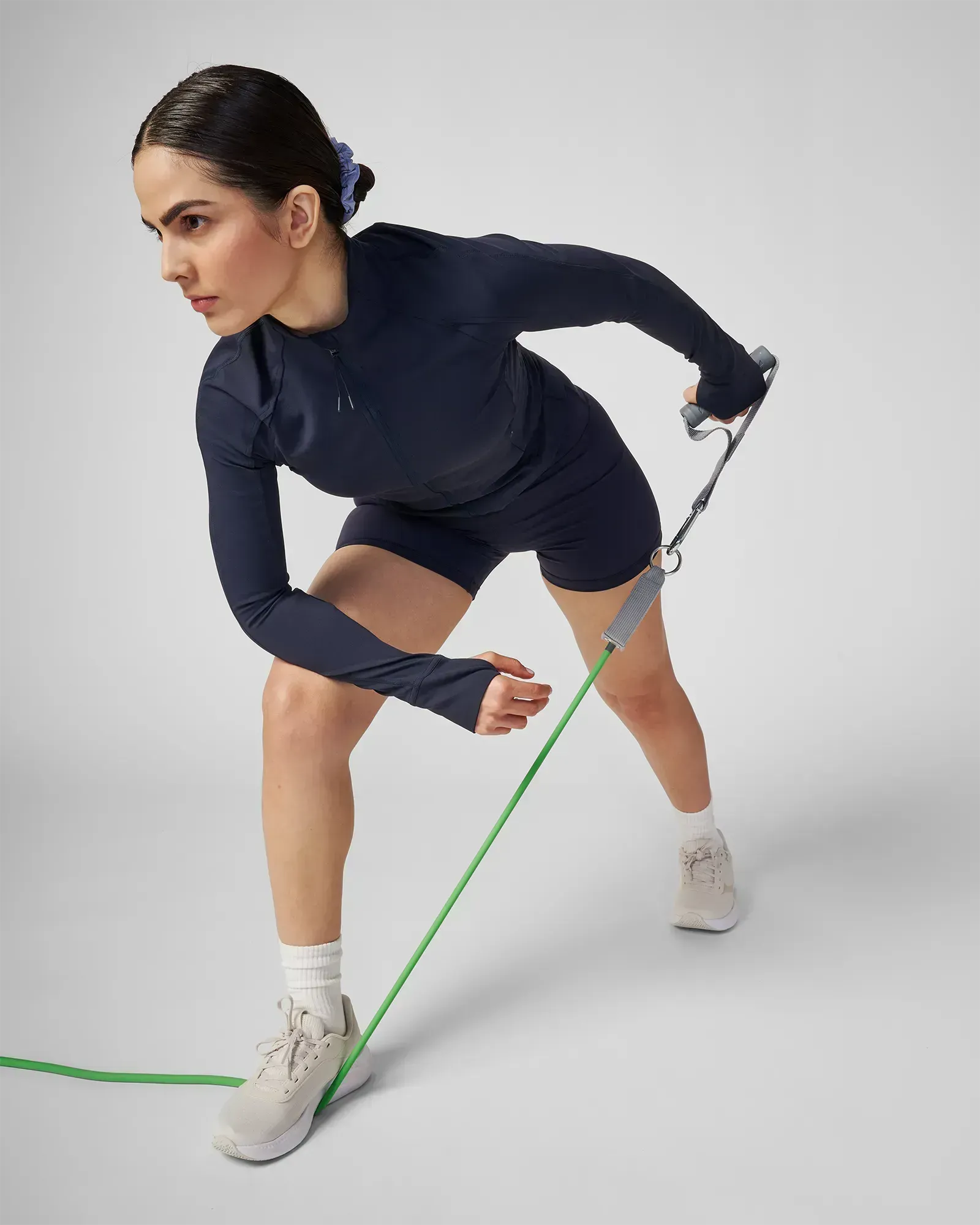 Woman performing a bent-over single-arm row in a staggered stance using EQYP Power Tubes 30 lbs green resistance tube with handle, side profile view