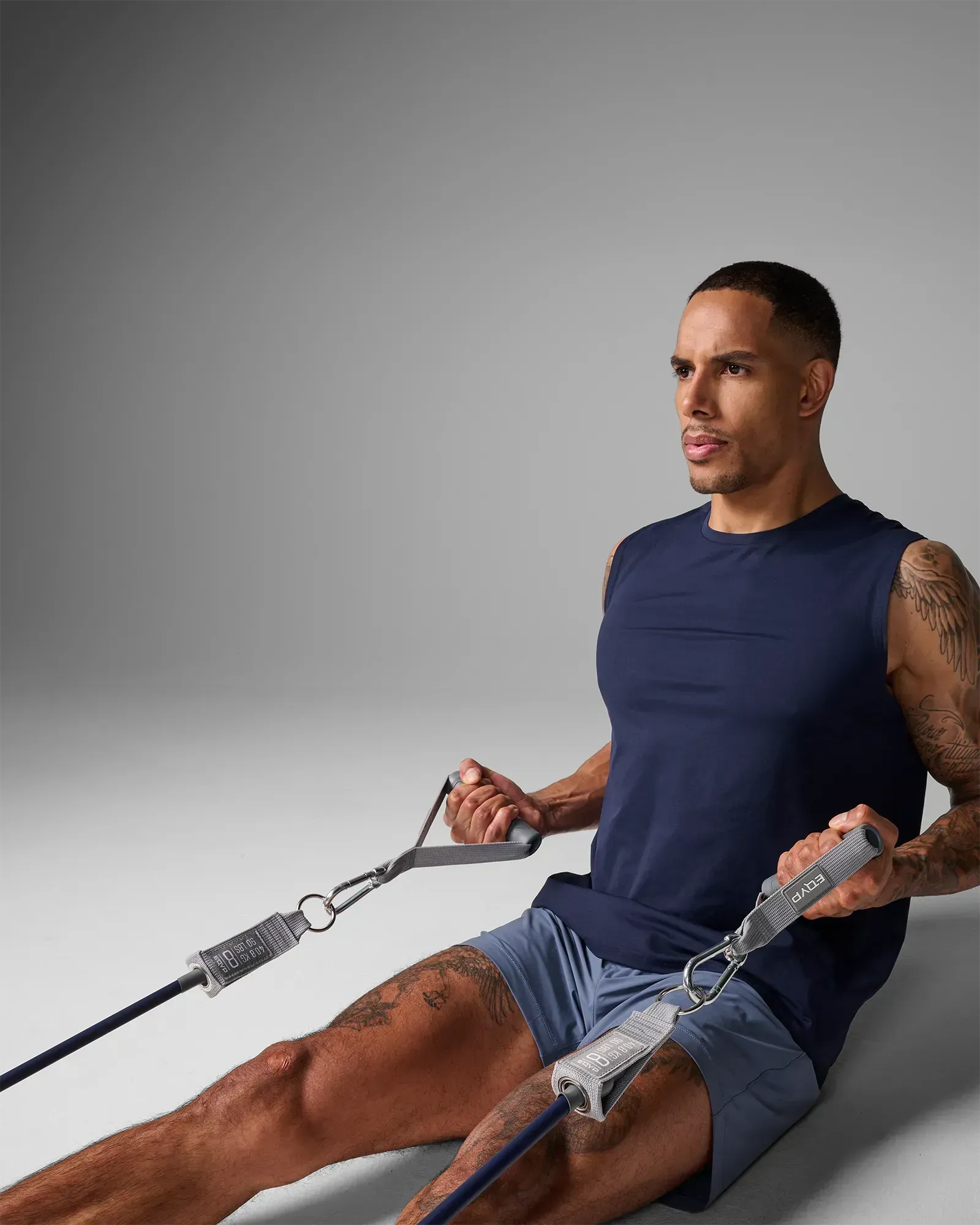 Man performing a seated bilateral row using EQYP Power Tubes 90 lbs navy blue resistance tube with handles, side profile view