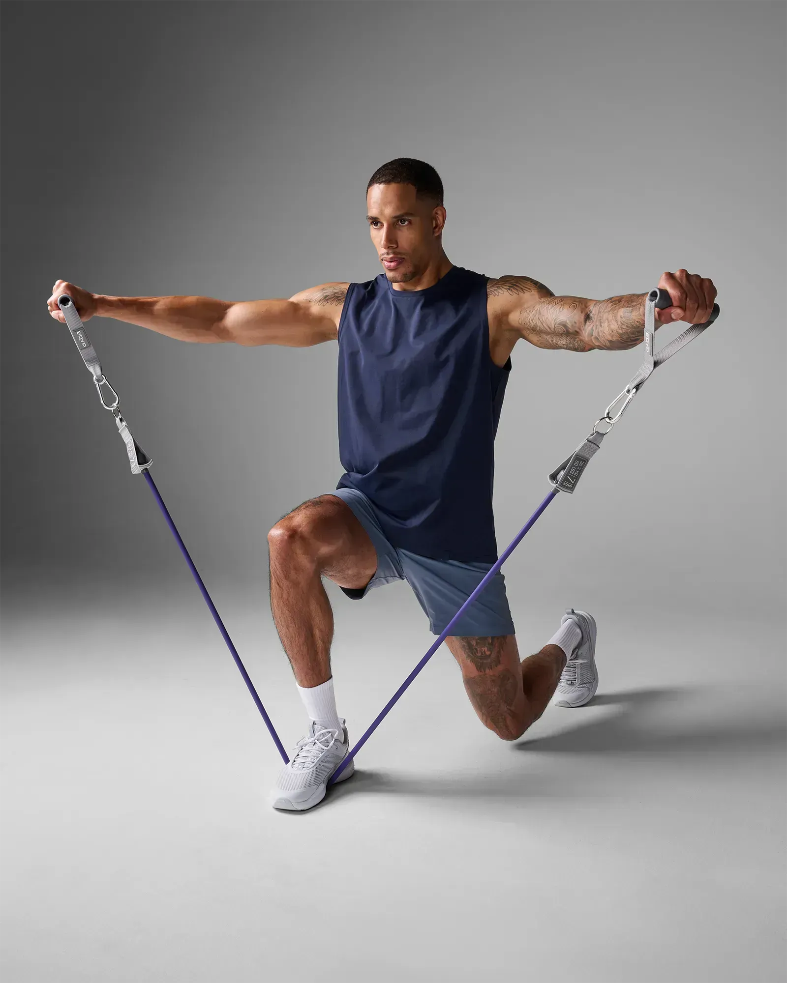Man performing a kneeling bilateral lateral raise using EQYP Power Tube 80 lbs purple resistance tube with gray handles