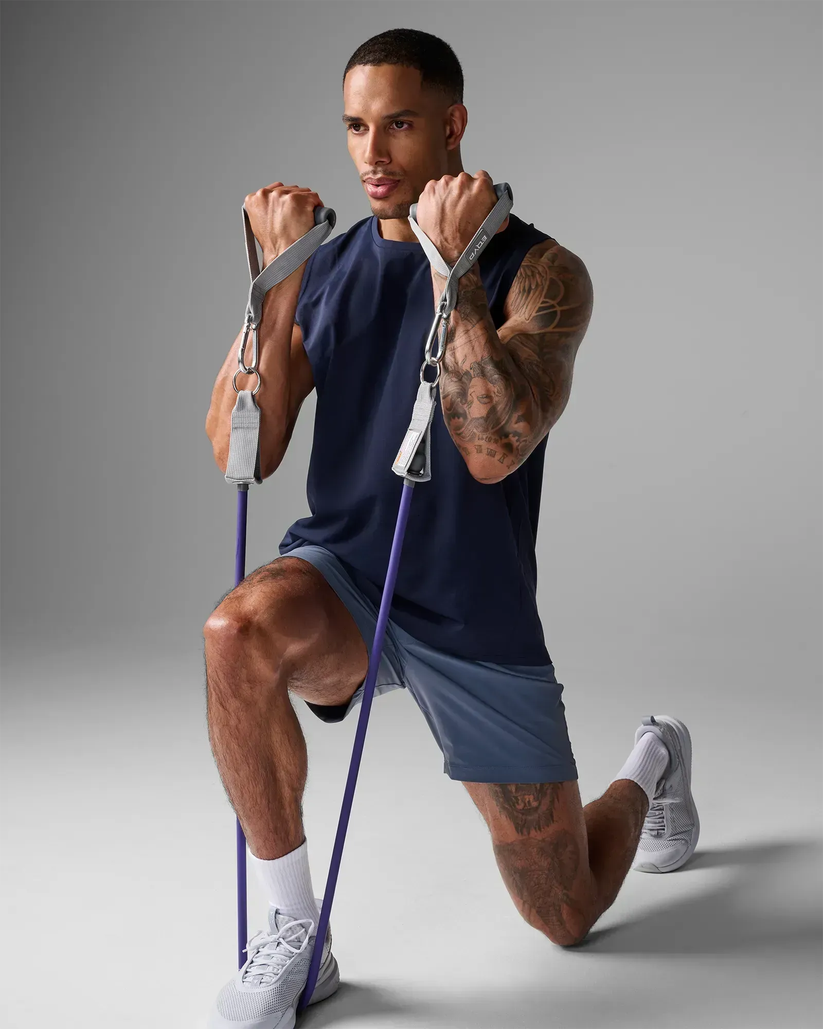 Man performing a kneeling bilateral bicep curl using EQYP Power Tube 80 lbs purple resistance tube with gray handles