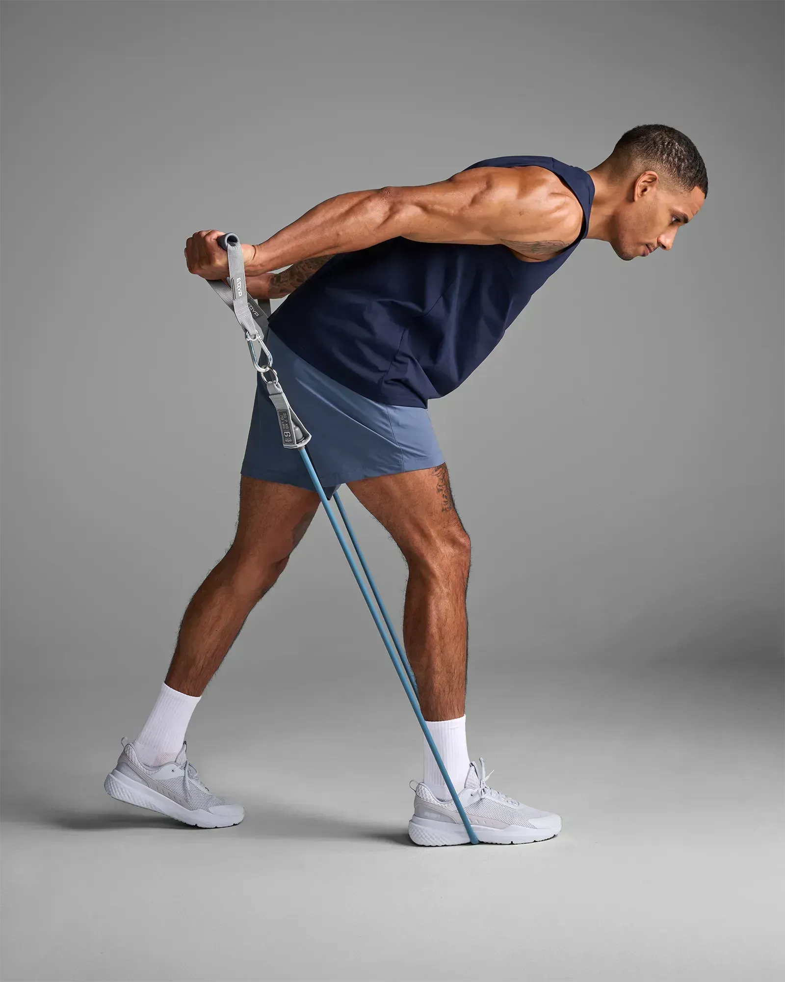 Man performing standing single-arm bent-over row with EQYP Power Tube to build unilateral back and bicep strength