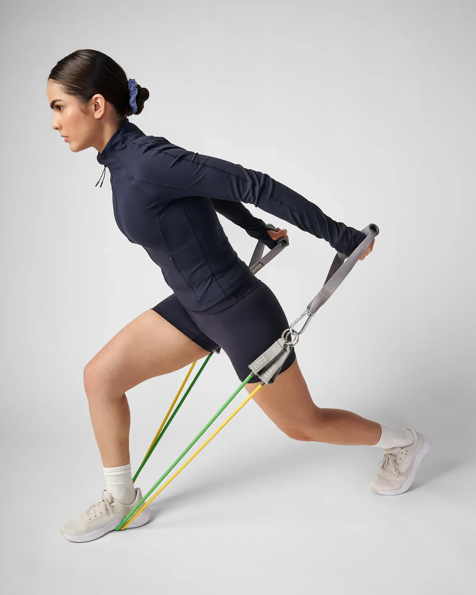 Woman performing a forward lunge with row using the EQYP Power 3 Strength Kit handles and stacked resistance tubes