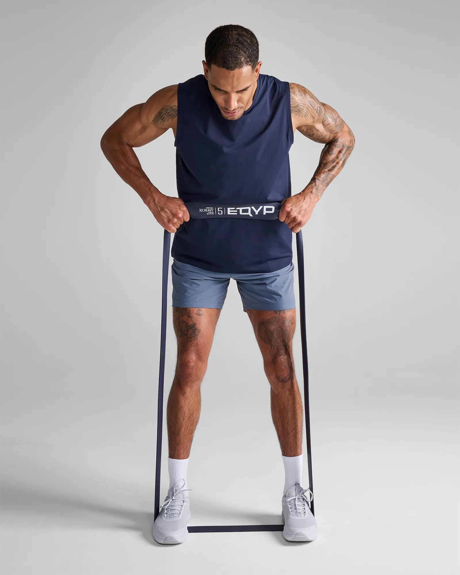 Man performing a standing bent over row using an EQYP dark gray elastic wide super band around his feet