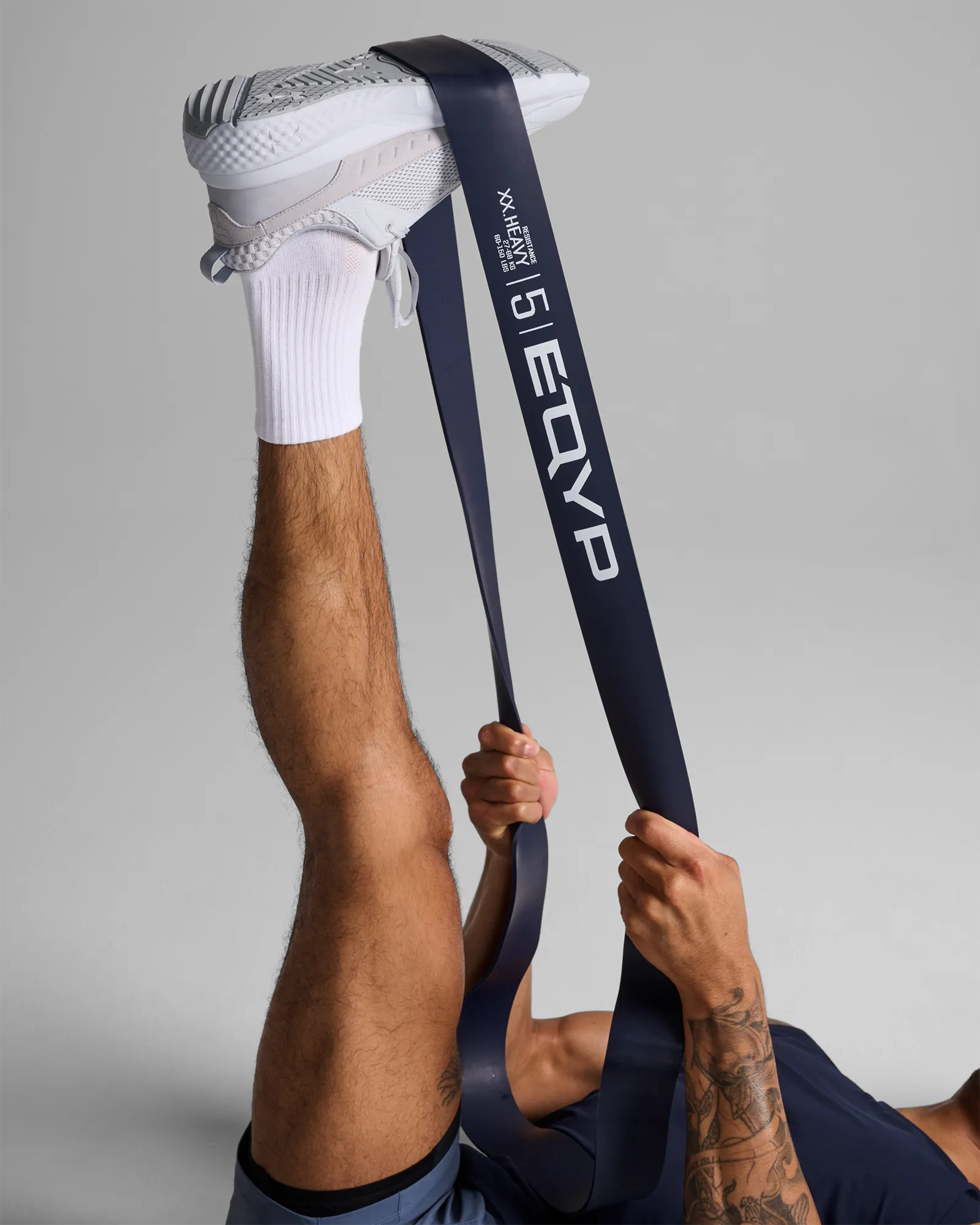 Man using EQYP Super Band to perform a lying single-leg hamstring stretch for post-workout flexibility and lower body recovery