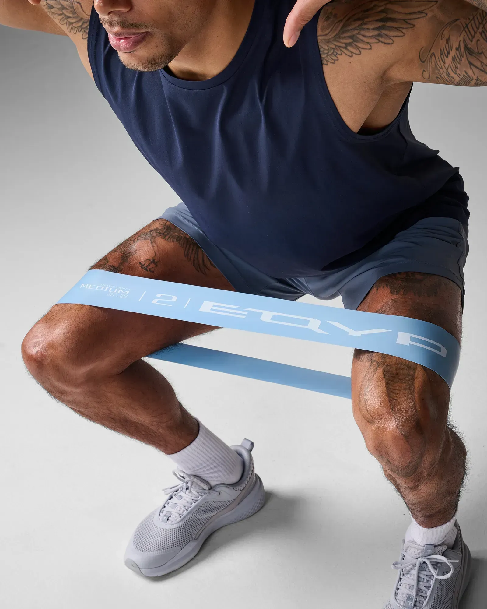 Man performing a squat using EQYP Ultimate Power Loop Medium light blue resistance band above the knees
