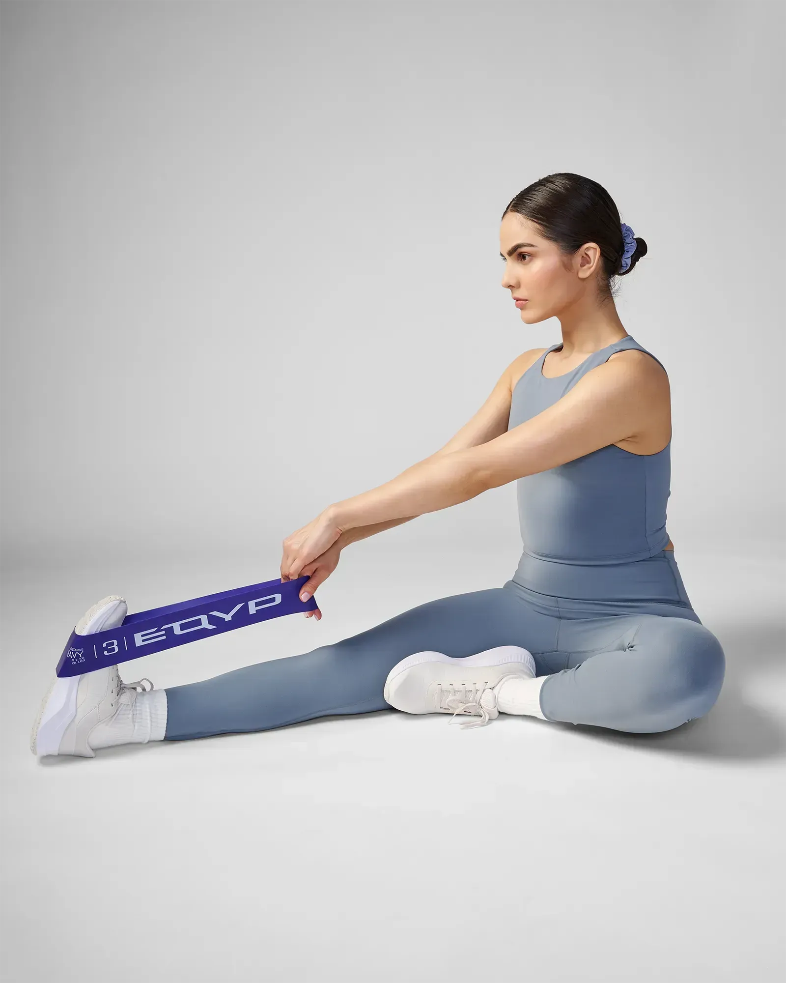 Woman performing a seated unilateral hamstring stretch using EQYP Advanced Power Loop Heavy purple resistance band