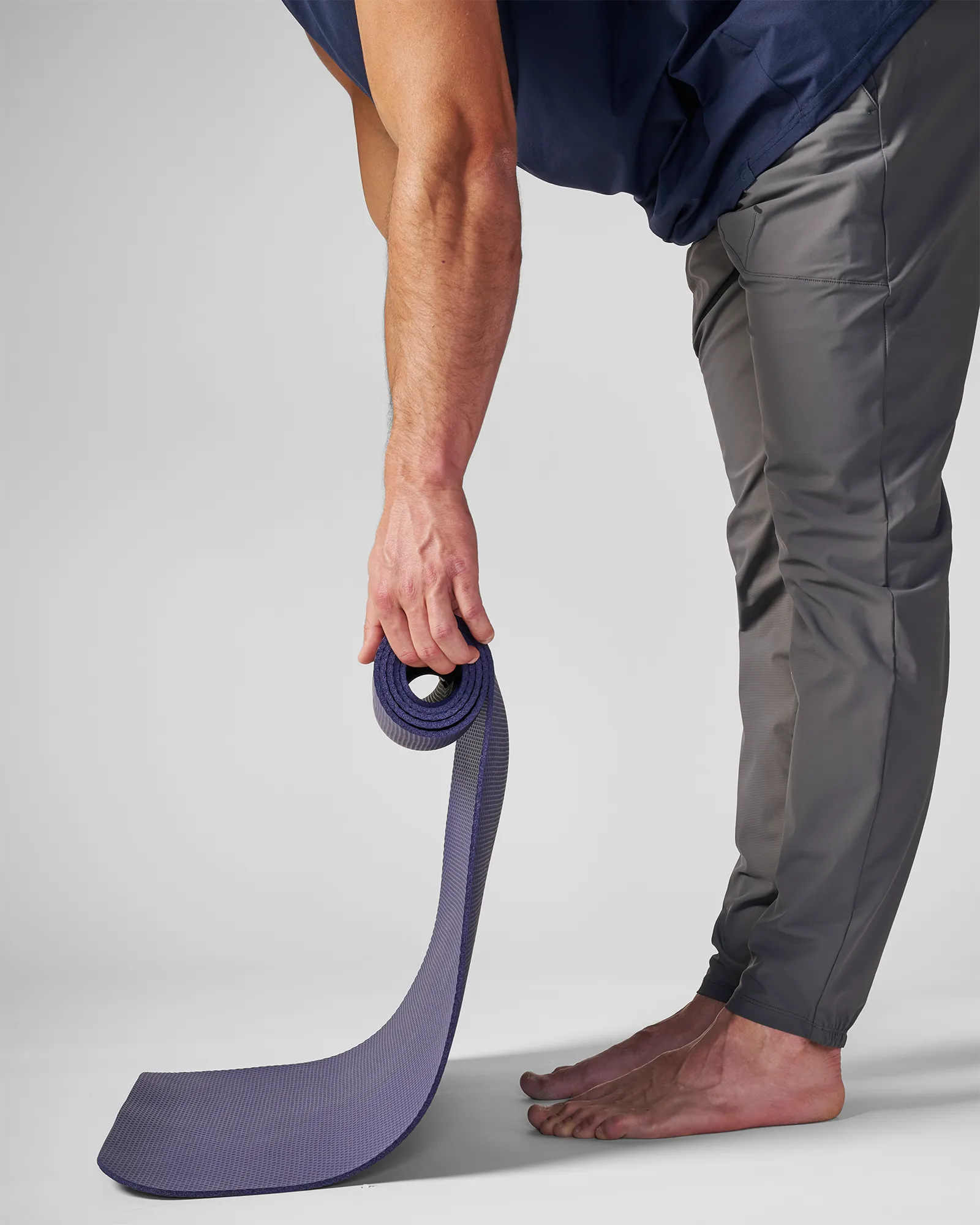 Man rolling up an EQYP yoga mat in navy blue