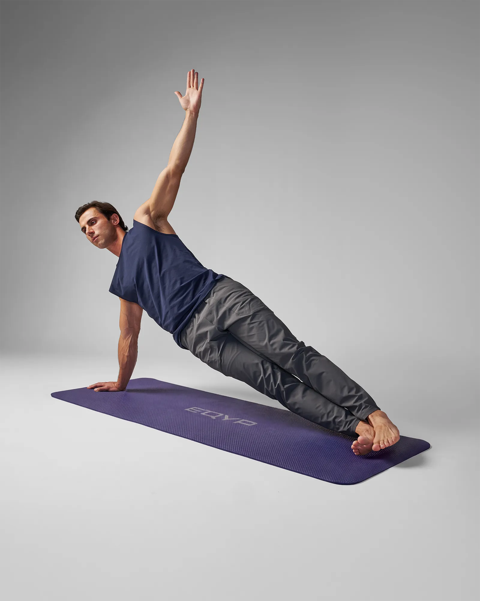 Man performing a side plank with a unilateral arm raise on an EQYP Yoga Mat in navy blue