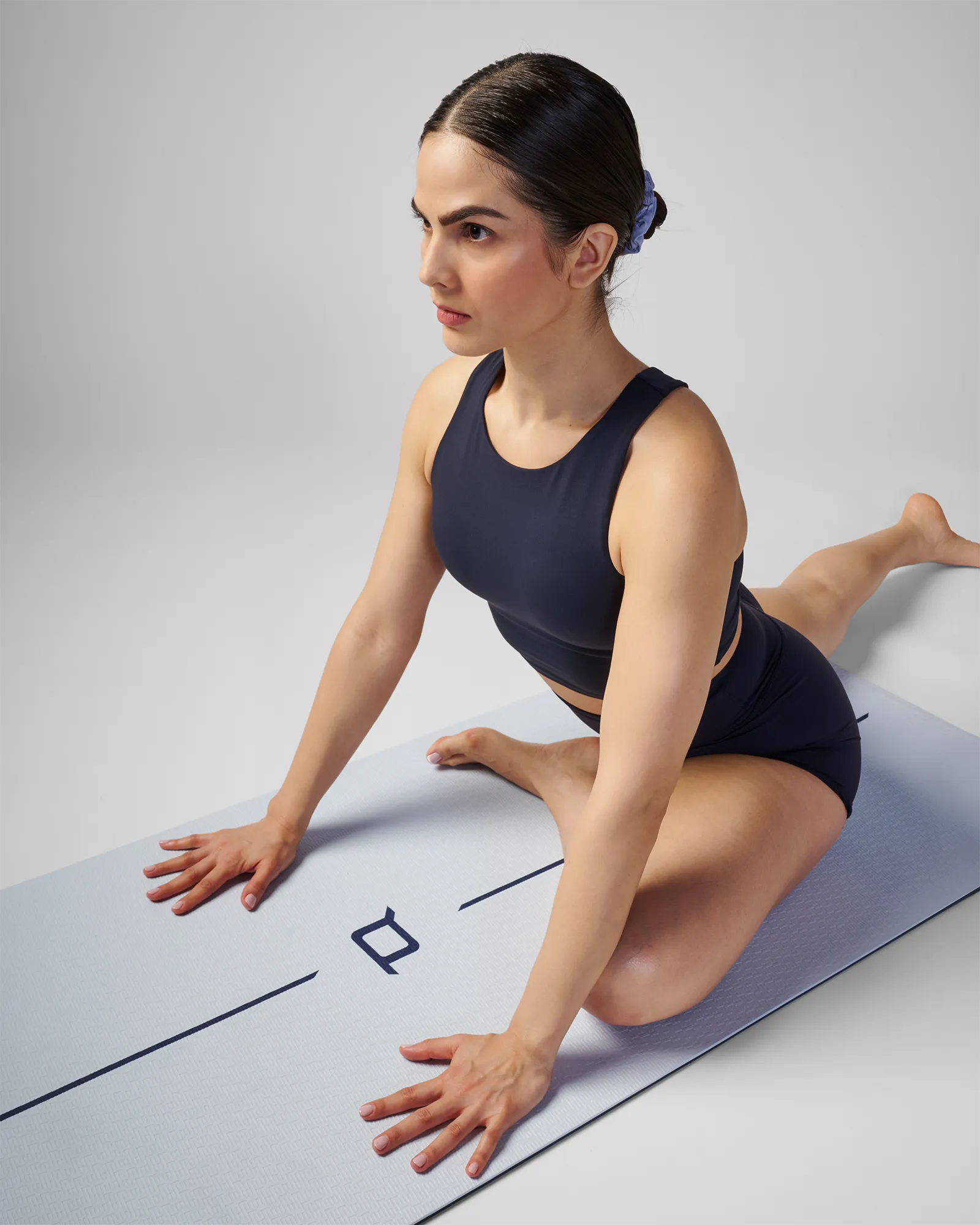 Woman on EQYP Dual Layer Yoga Mat showing light blue side performing pigeon pose