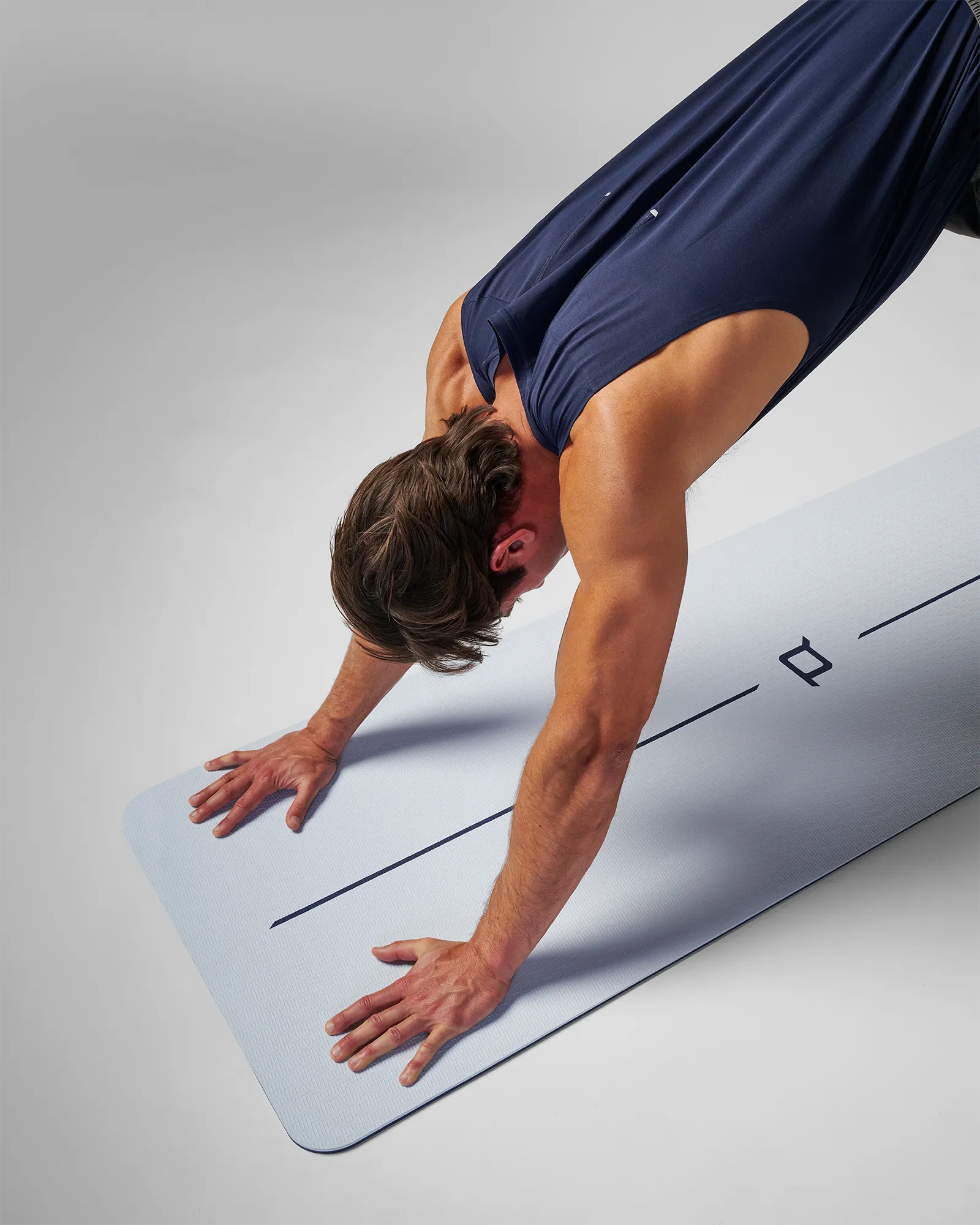 Man on EQYP Dual Layer Yoga Mat showing light blue side performing downward dog