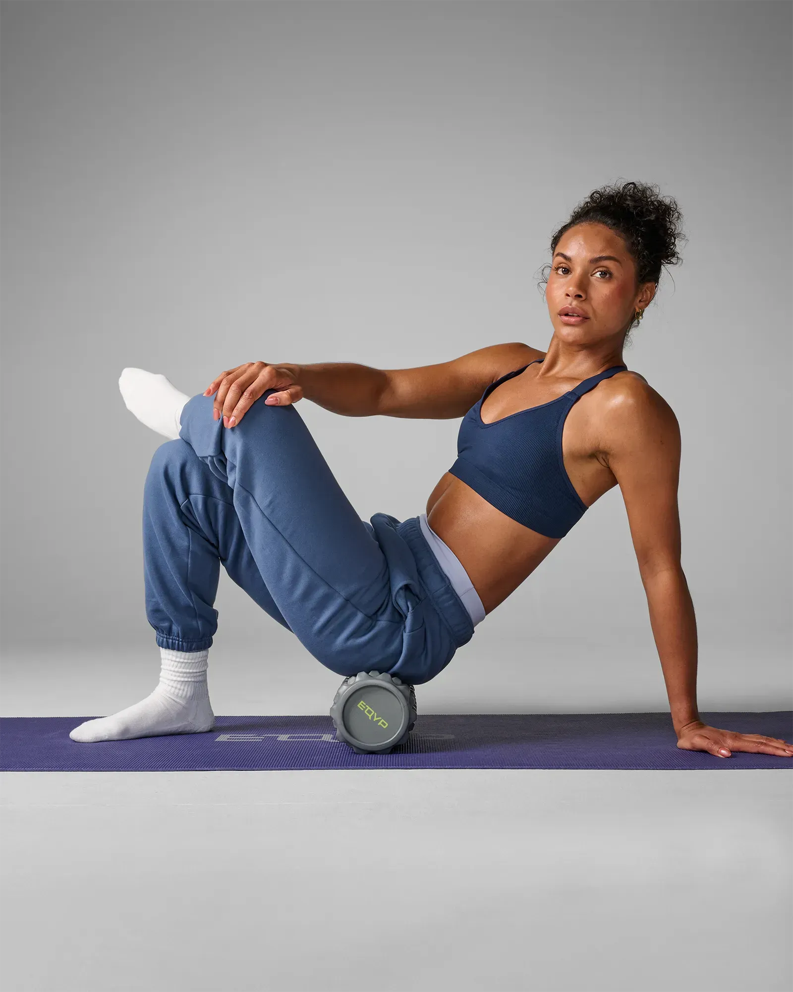 Woman on yoga mat rolling on extreme 12 Inch EQYP foam roller