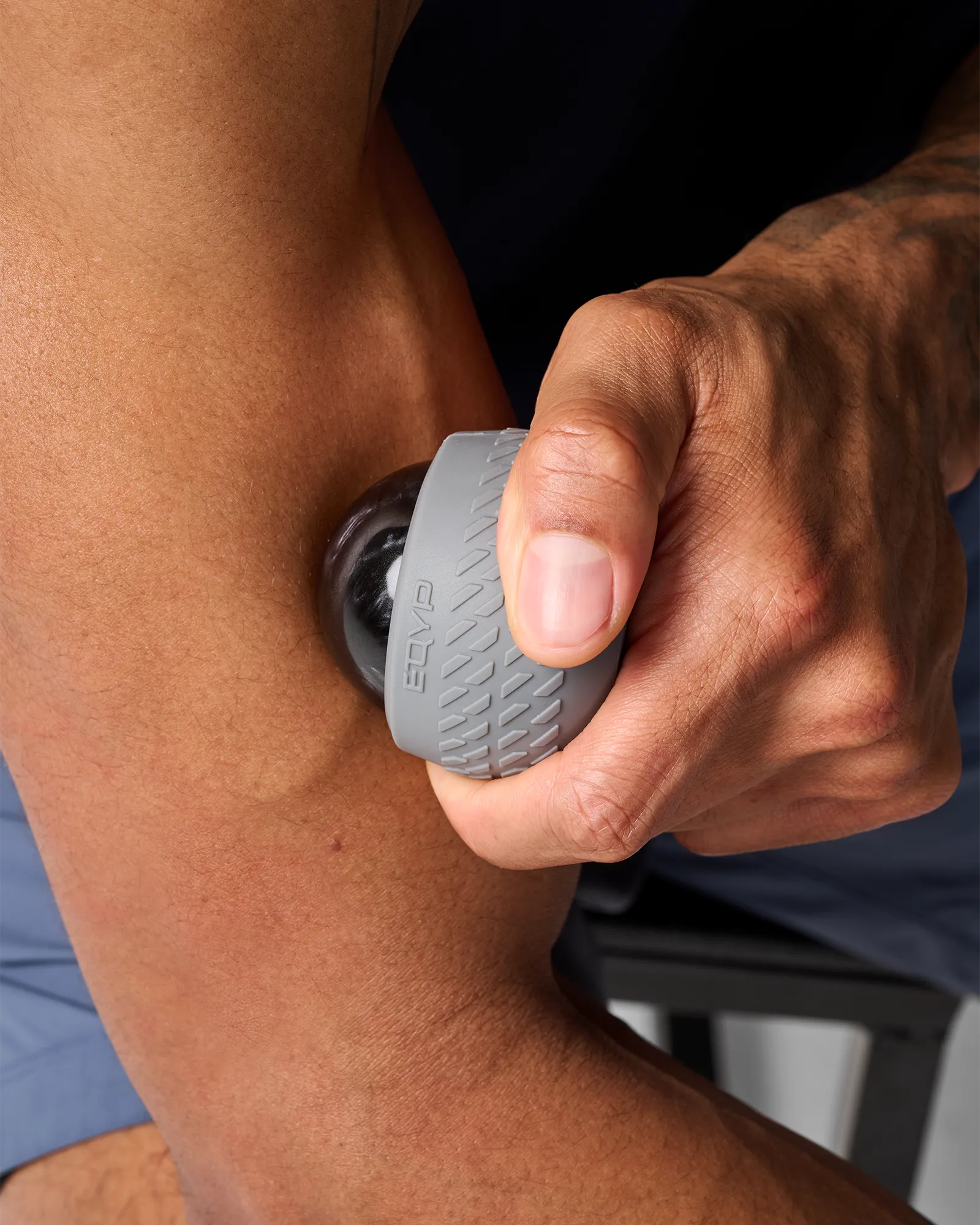 Man using EQYP roll-on massager with textured outer shell on bicep