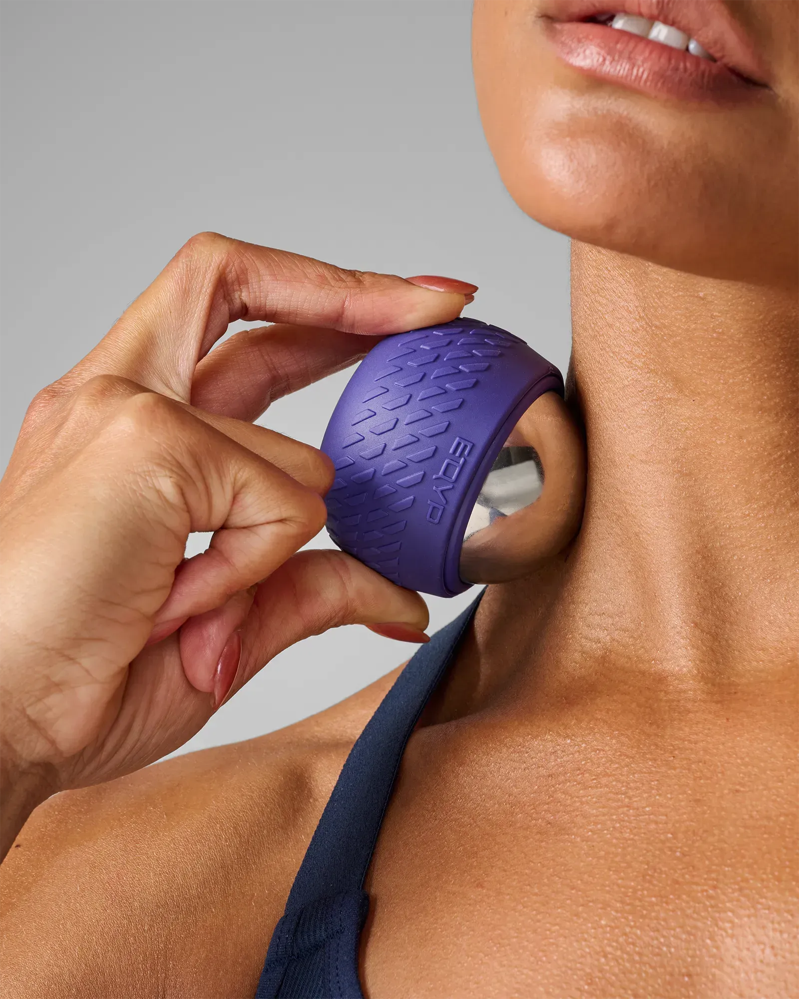 Woman using stainless steel core EQYP roll-on massager with textured outer shell on neck
