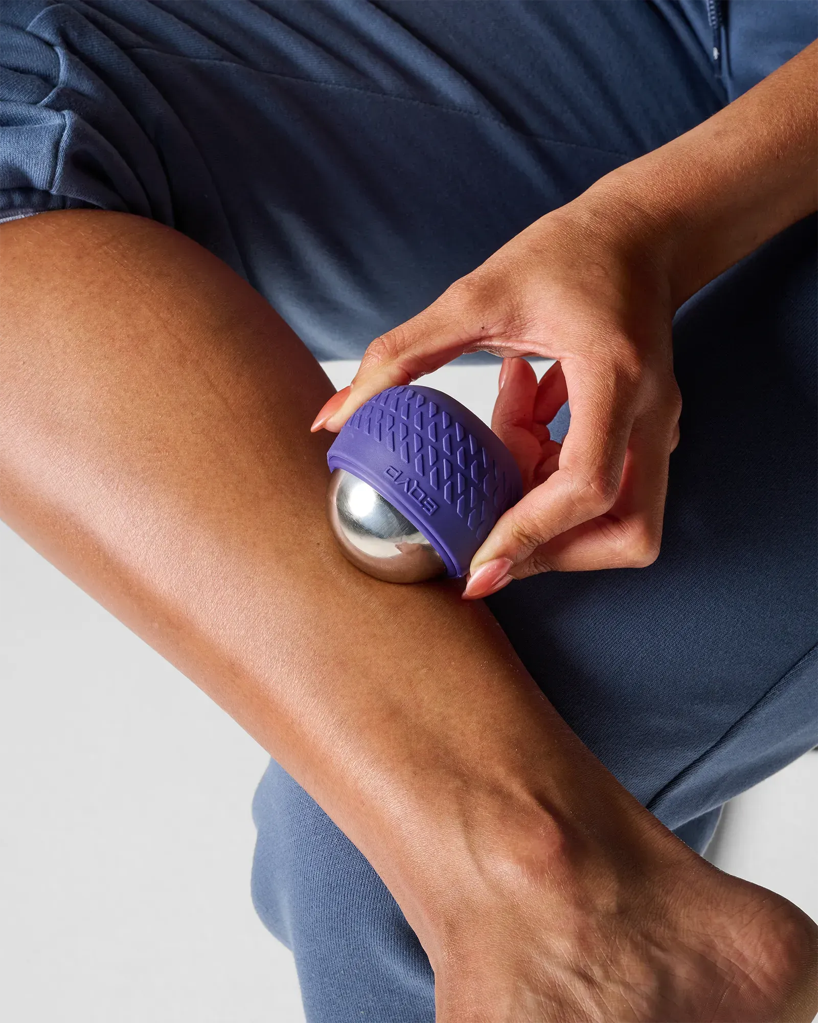 Woman pressing EQYP Iceworks Cold Roll-On Massager on knee for cold compression therapy and joint inflammation relief