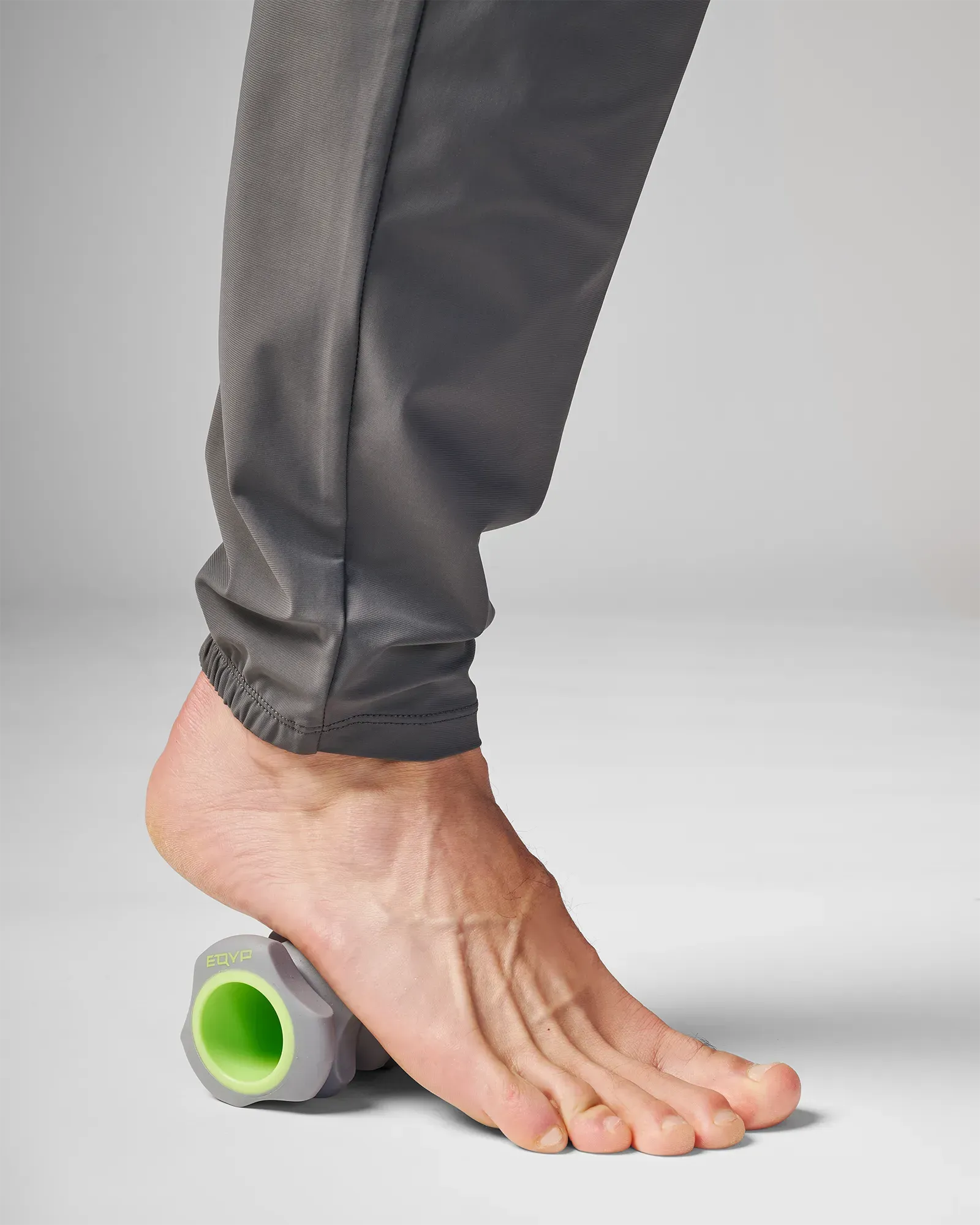 Man pressing EQYP Foot and Hand Roller under arch of foot to relieve plantar fascia tension and improve foot mobility