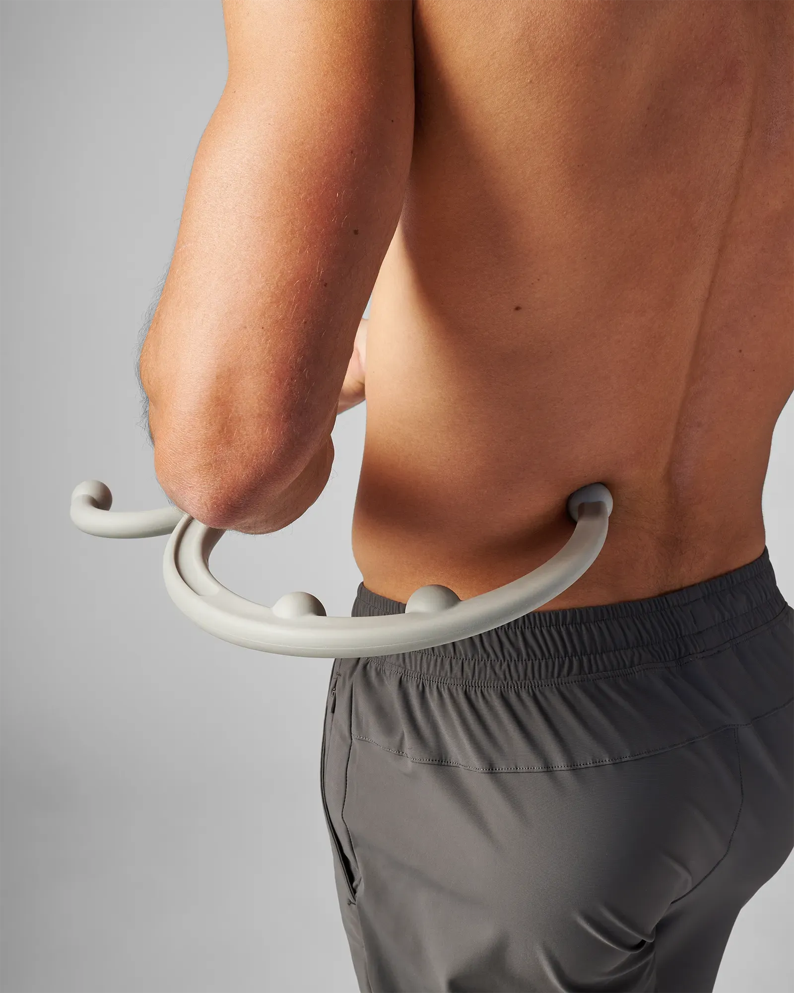 Man using EQYP muscle hook recovery massager tool on his lower back