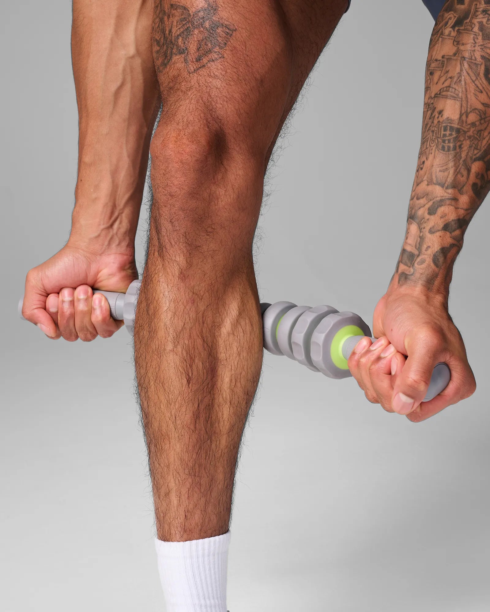 Man using 19 inch EQYP massager bar on calf