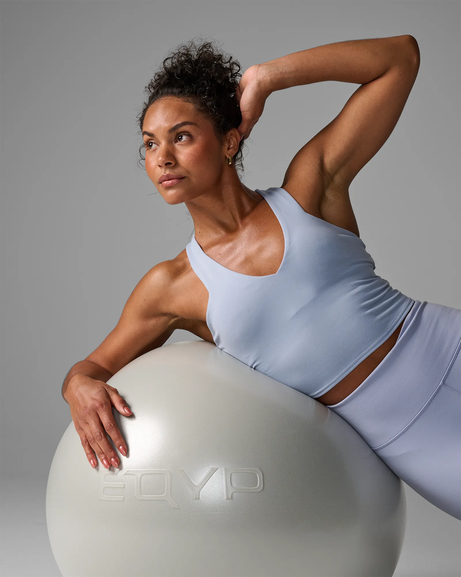 Woman performing a stability ball side bend using an EQYP Pro Stability Ball 55cm in pearl white with torso draped over the ball
