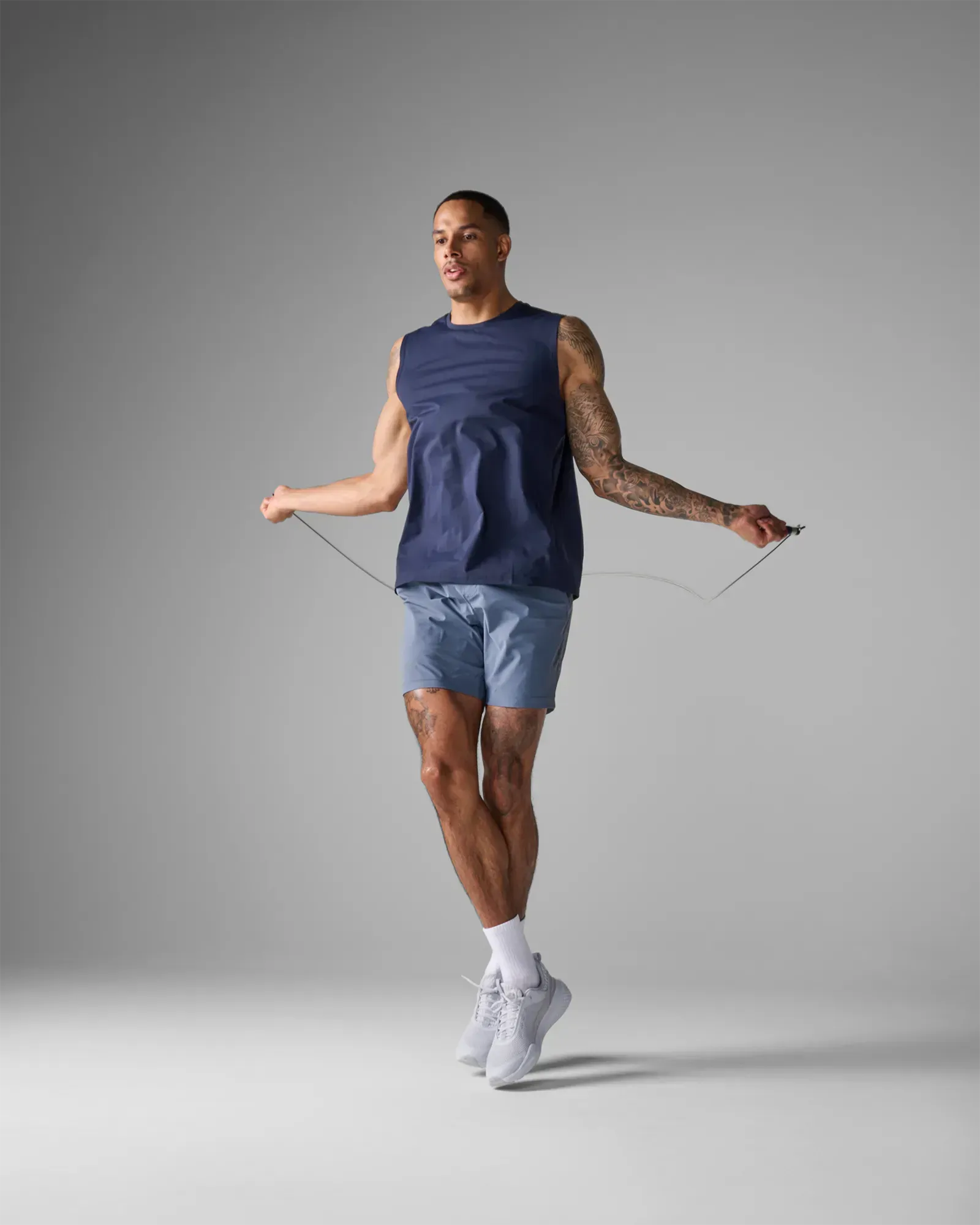 Man jumping rope using EQYP Pro Cable Jump Rope with navy blue and aluminum handles and steel cable