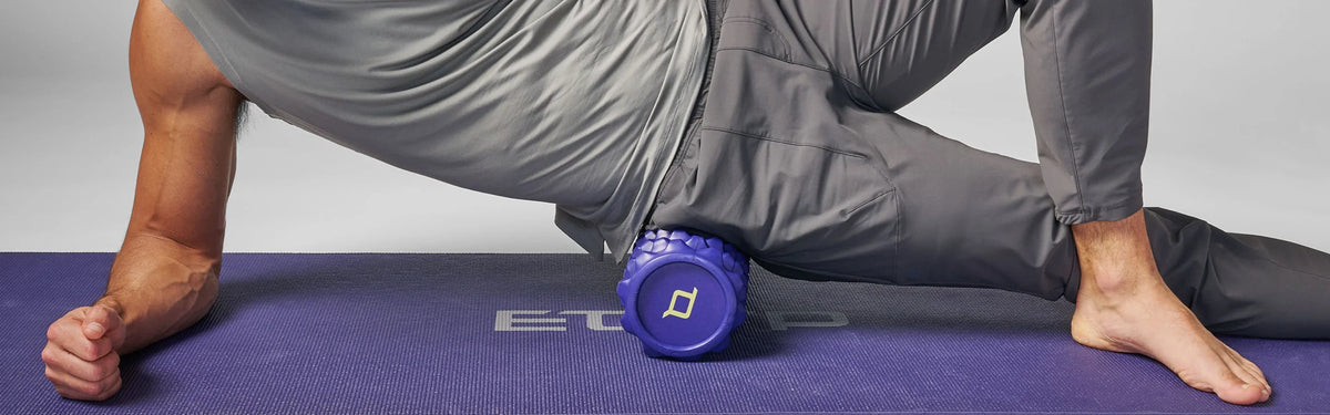 Close-up of a person using a purple textured EQYP foam roller on their outer thigh to ease muscle soreness.