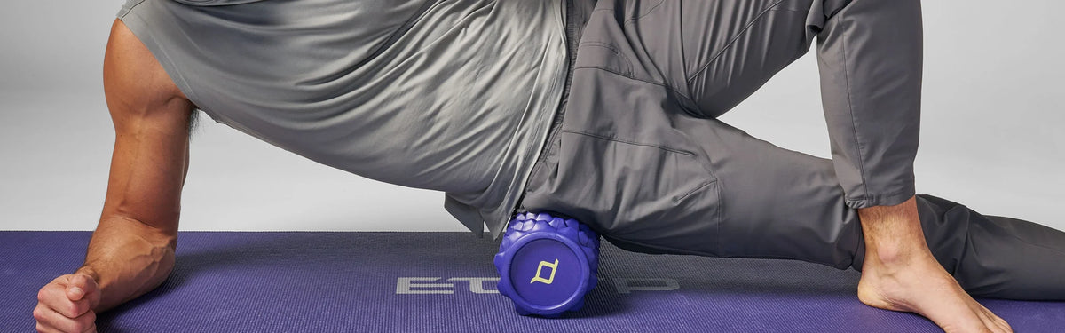 Close-up of a person rolling a purple EQYP textured foam roller along their inner thigh in a lunge position.