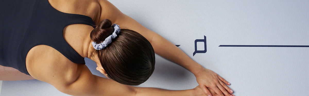 Overhead view of a woman in a seated forward fold stretch on a EQYP Dual Layer Yoga Mat.