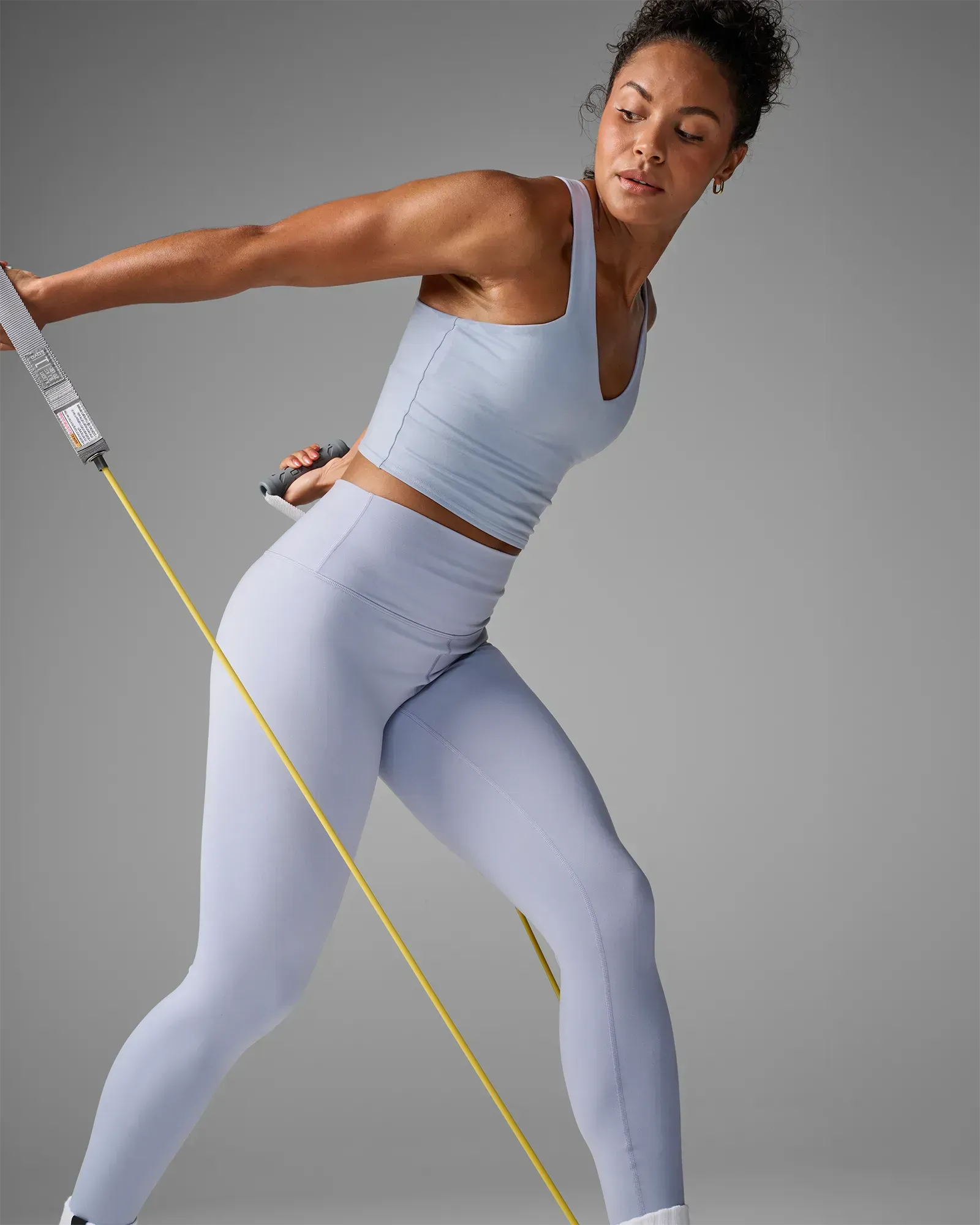 Woman performing a standing single-arm row using EQYP Power Tubes with Handles Extra Light
