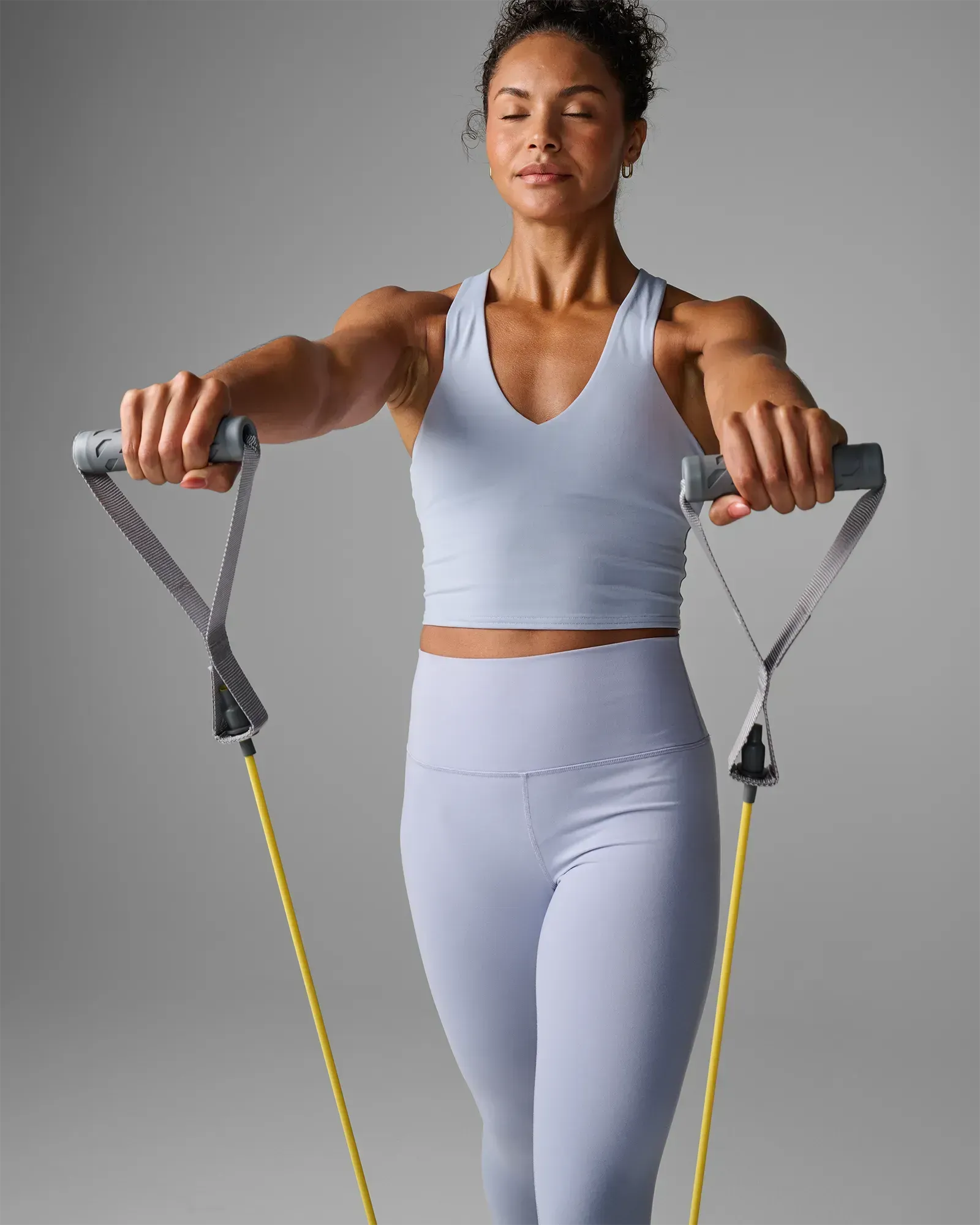 Woman performing a standing overhand front fly extension using EQYP Power Tubes with Handles Extra Light