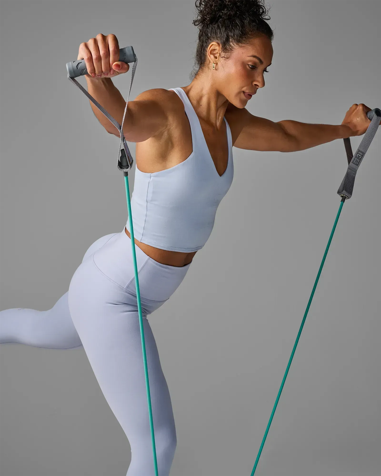 Woman performing a standing bilateral chest fly using EQYP Power Tubes with Handles Medium teal resistance tube