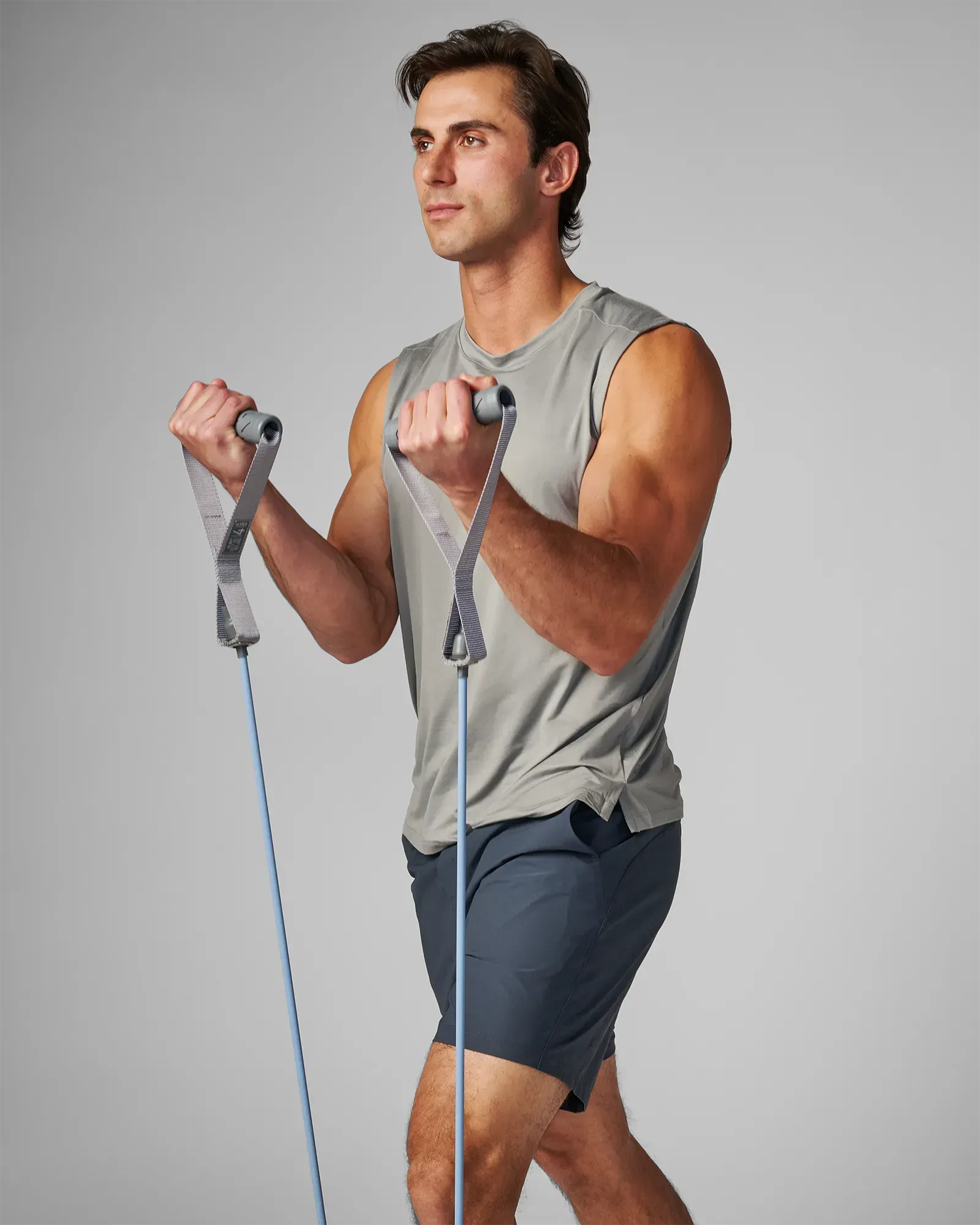 Man performing a standing bilateral bicep curl using EQYP Power Tubes with Handles Heavy blue resistance tube
