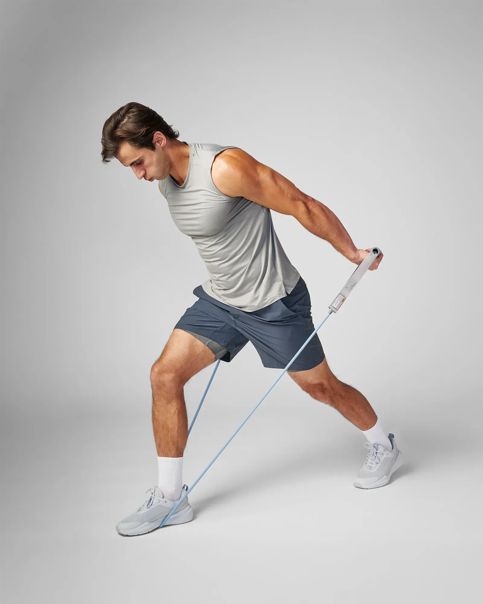 Man performing a bent-over unilateral tricep extension using EQYP Power Tubes with Handles Heavy blue resistance tube