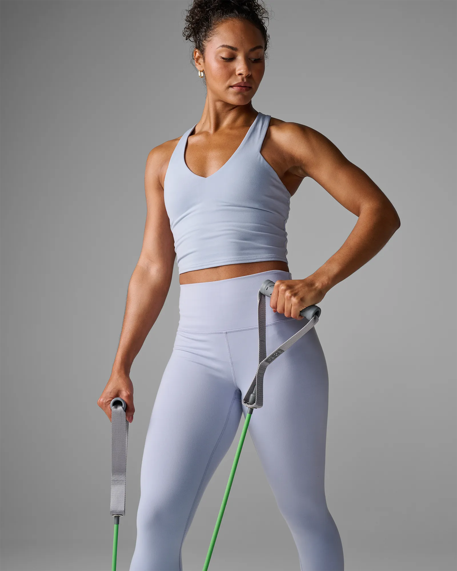 Woman performing a standing bilateral bicep row using EQYP Power Tubes with Handles green resistance tube