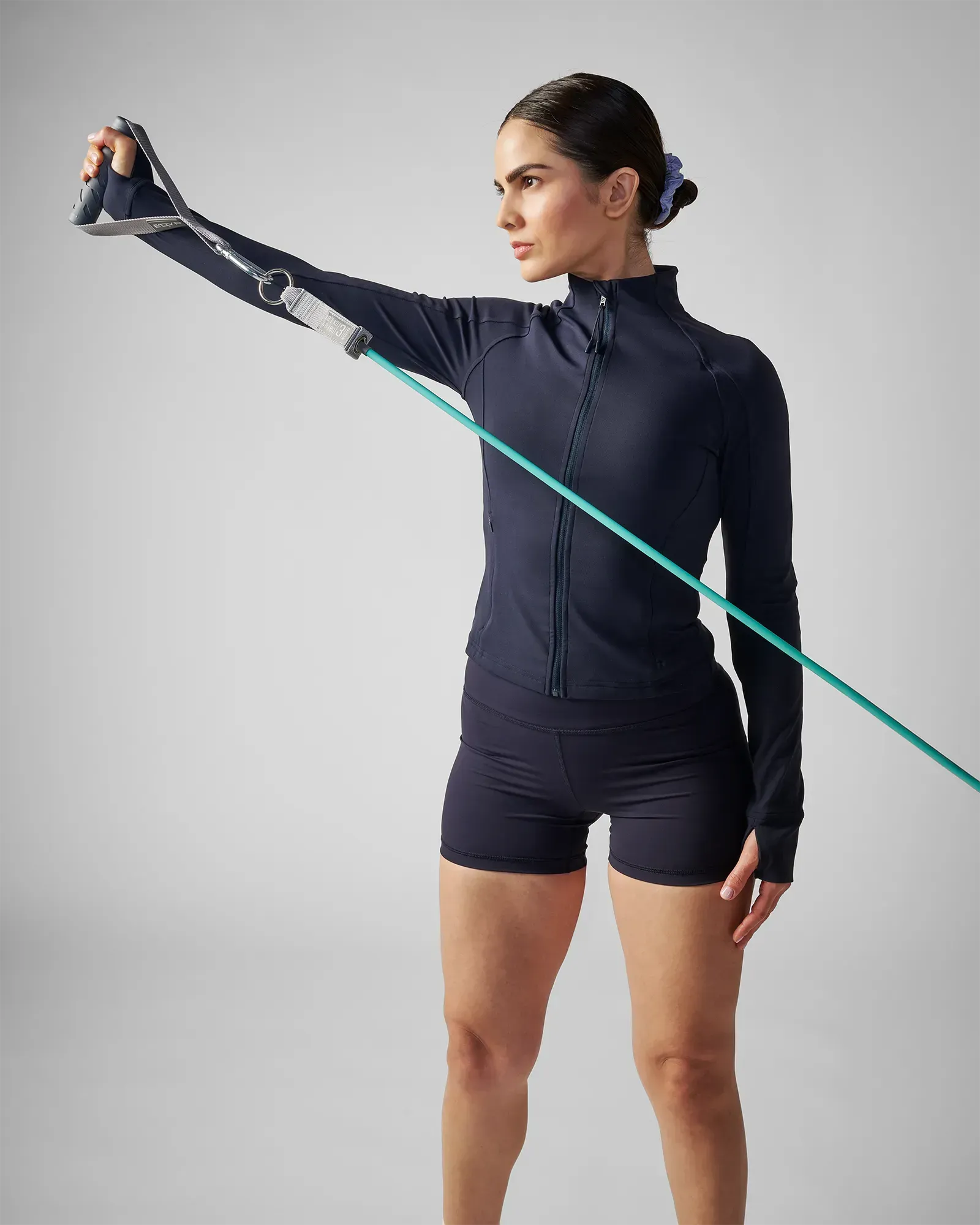 Woman performing a standing single-arm lateral raise using EQYP Power Tubes 40 lbs teal resistance tube with handle, side profile view
