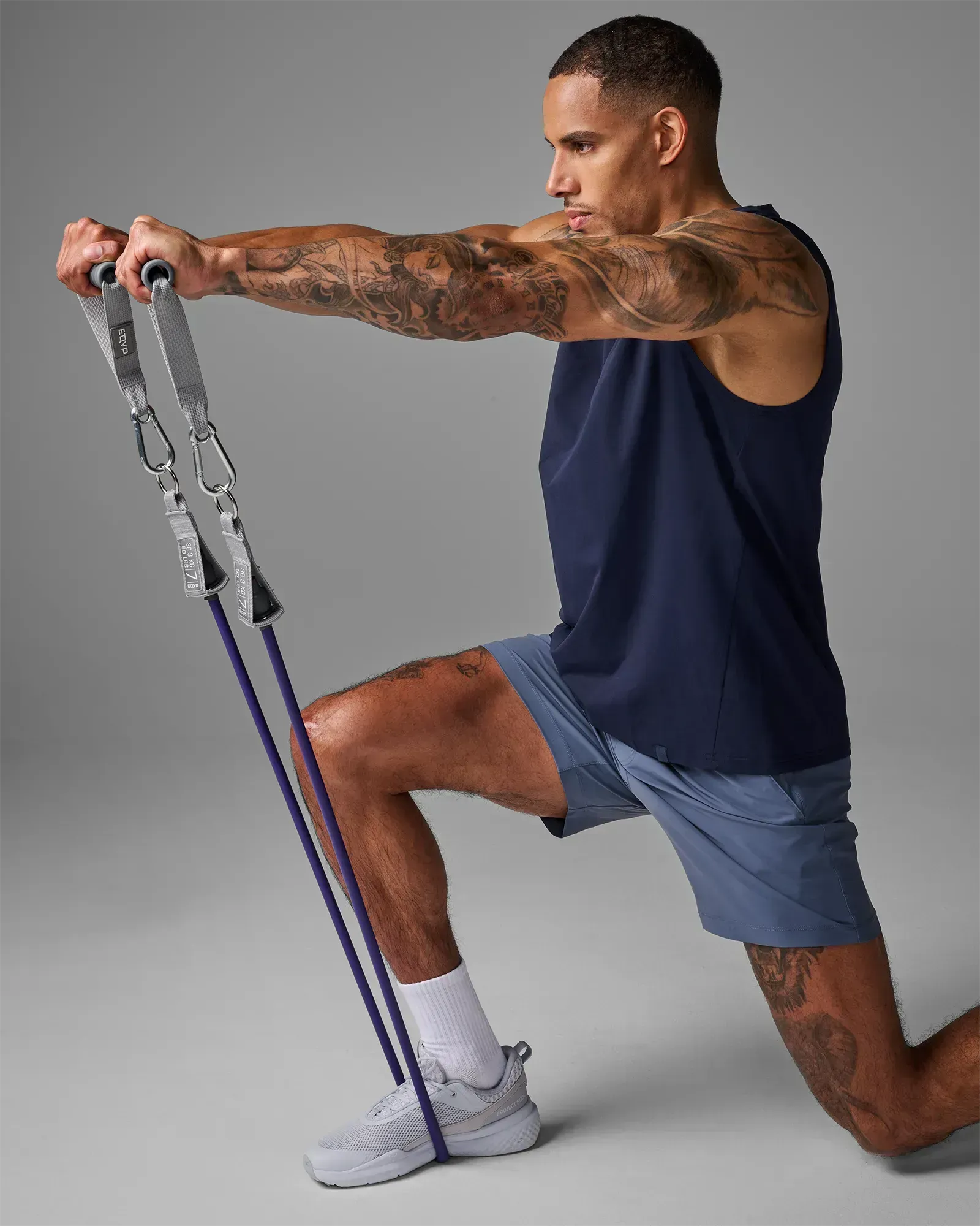 Man performing a kneeling bilateral chest press using EQYP Power Tube 80 lbs purple resistance tube with gray handles