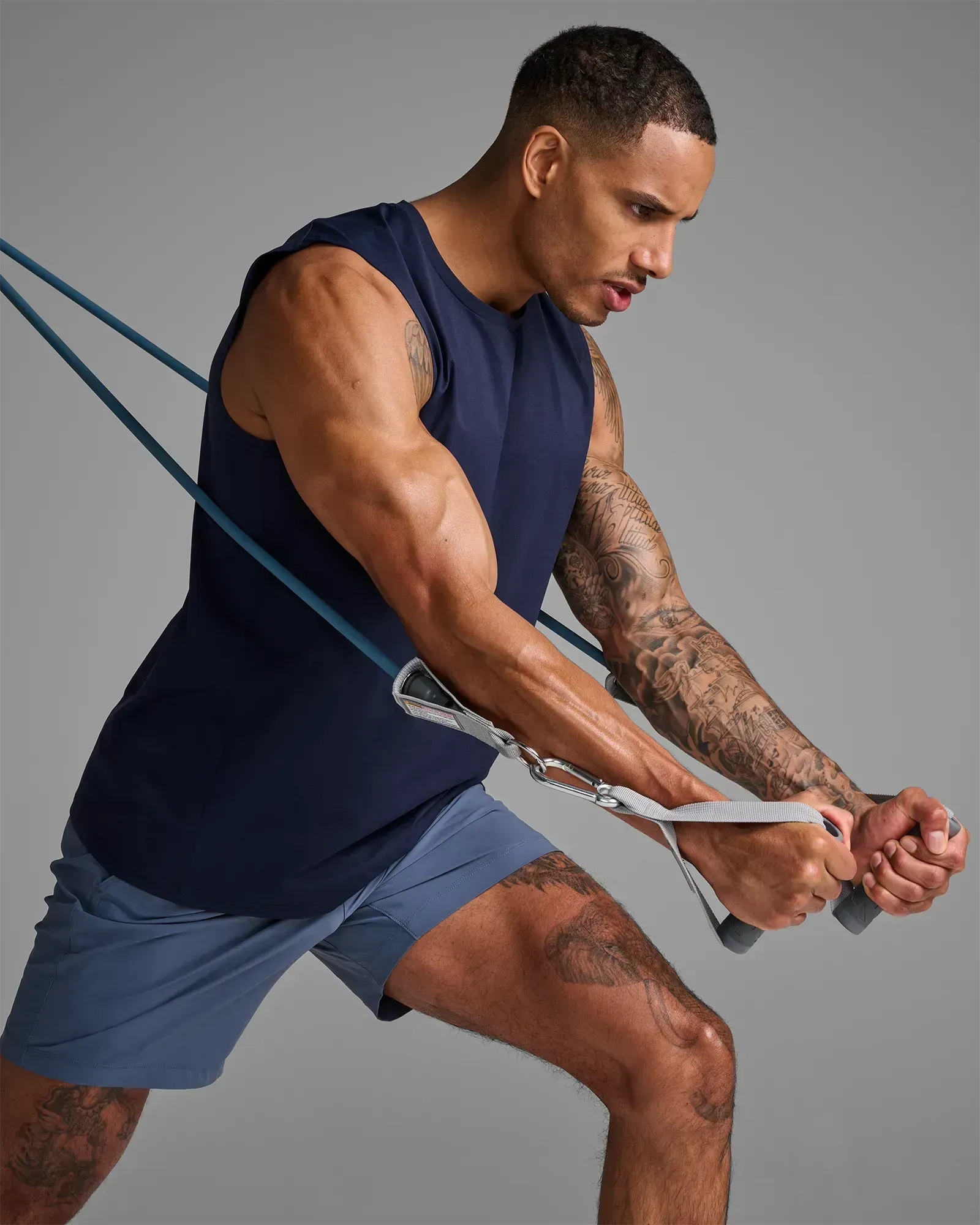 Man performing a standing unilateral low cable row using EQYP Power Tube 70 lbs blue resistance tube with gray handle