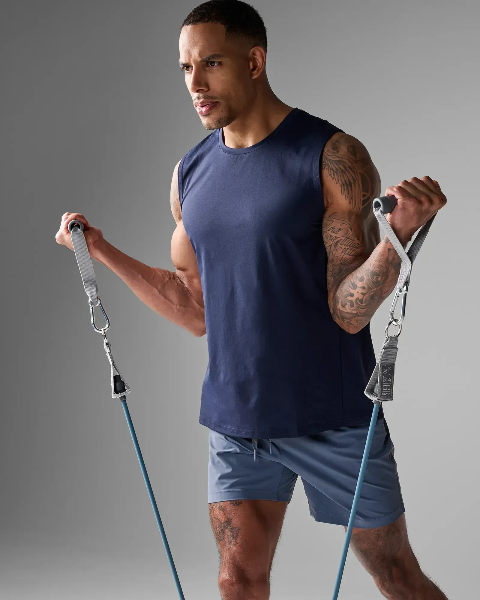 Man performing a standing bilateral bicep curl using EQYP Power Tube 70 lbs blue resistance tube with gray handles