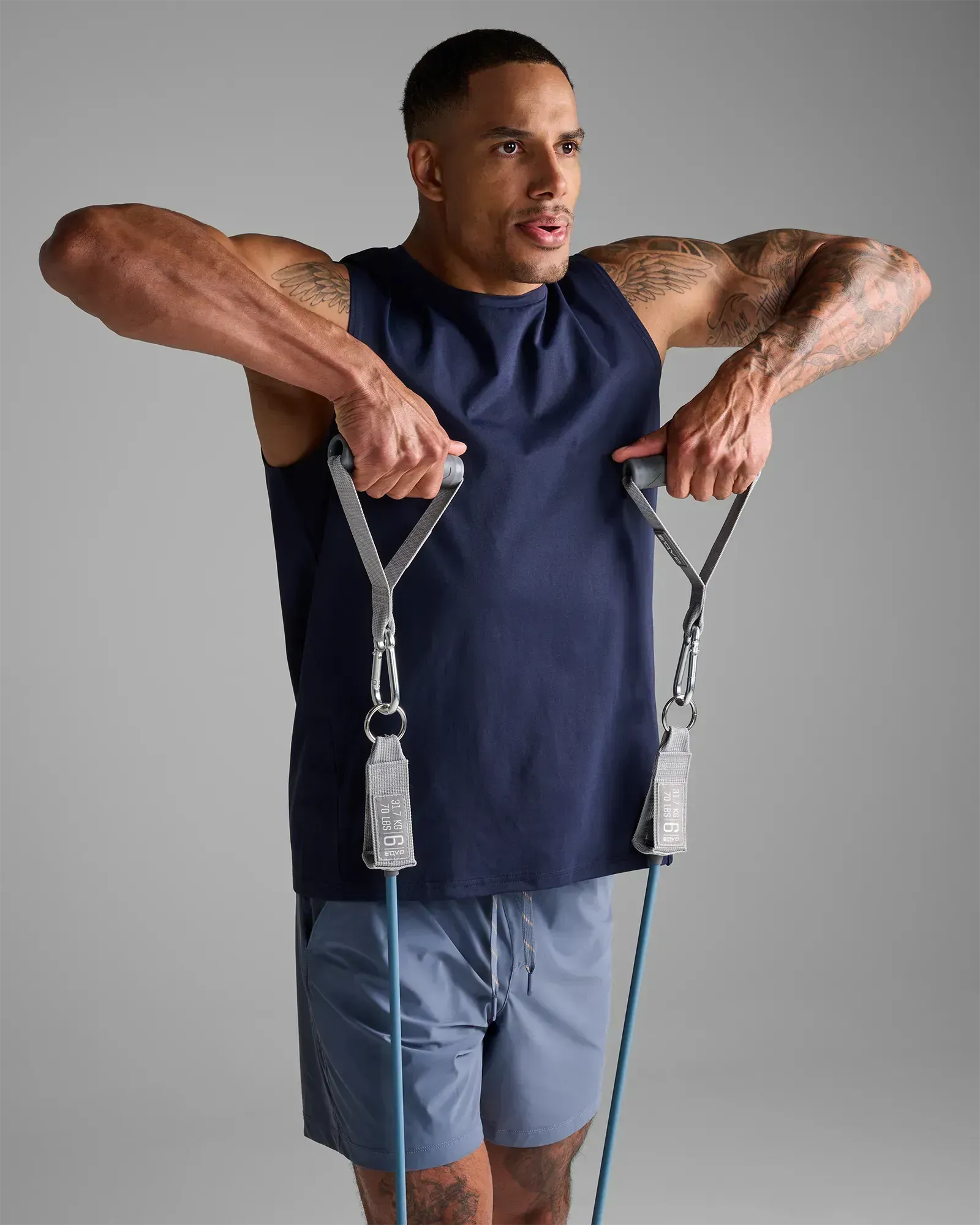 Man performing a standing bilateral upright row using EQYP Power Tube 70 lbs blue resistance tube with gray handles