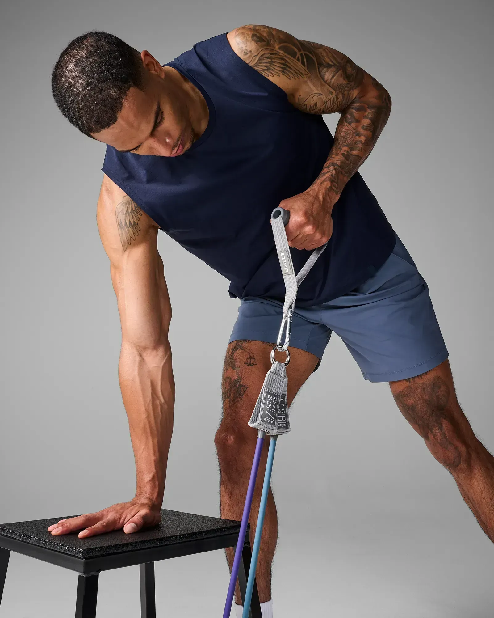 Man performing supported single-arm row with EQYP Power Tube braced on bench to isolate lat and upper back muscles
