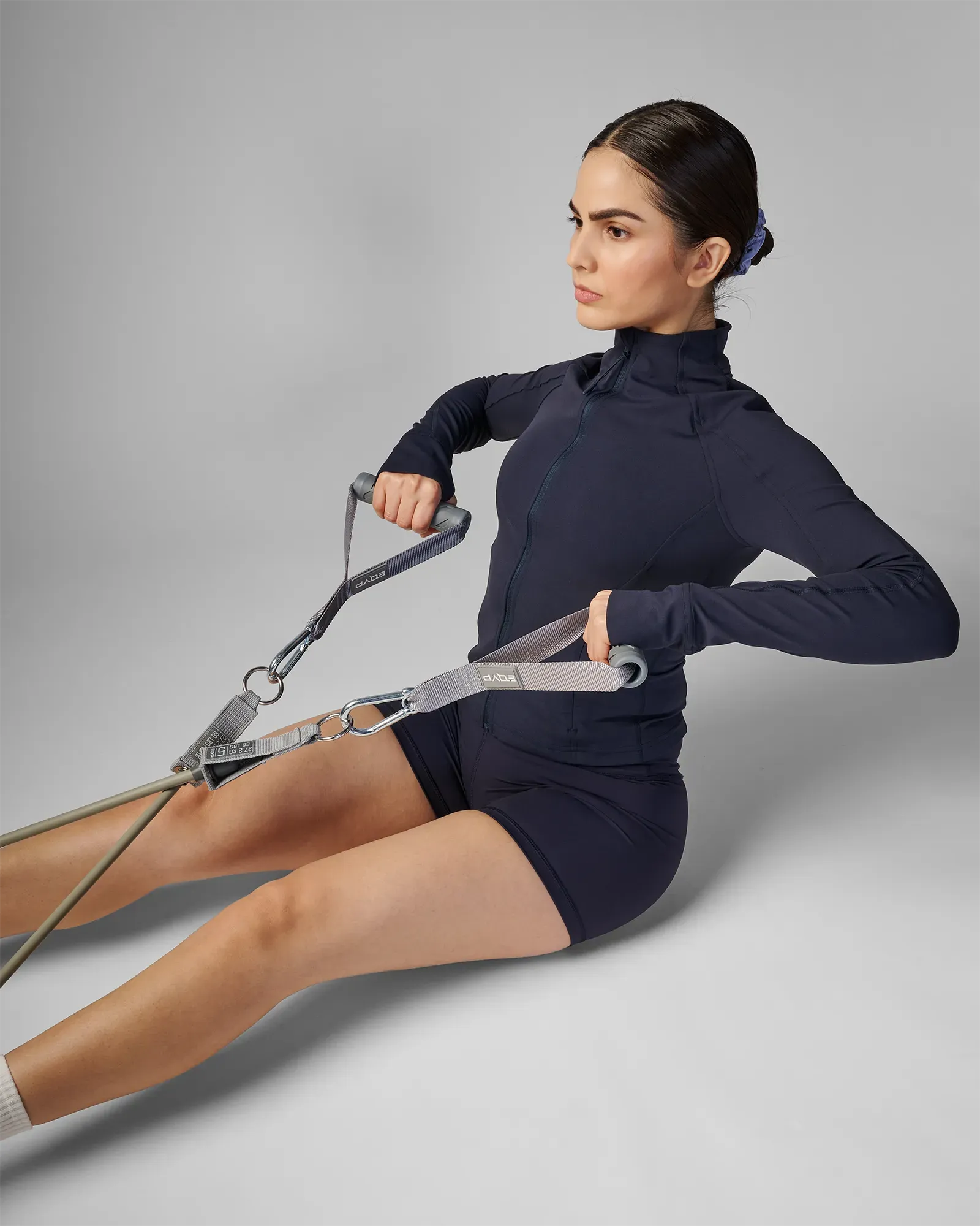 Woman performing a seated bilateral row using EQYP Power Tube Extra Heavy gray resistance tube