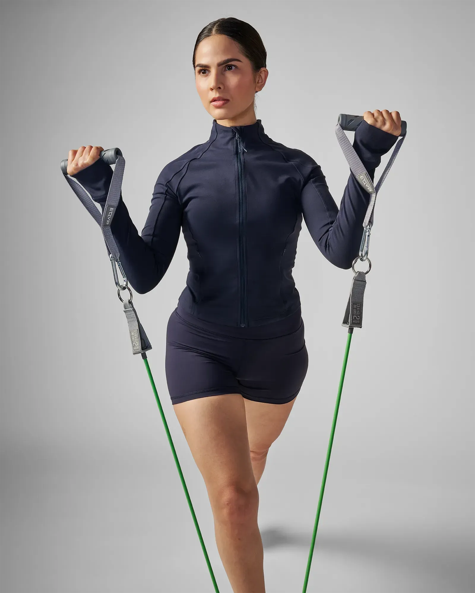 Woman performing a standing lateral raise using the EQYP Power 3 Strength Kit handles and resistance tubes