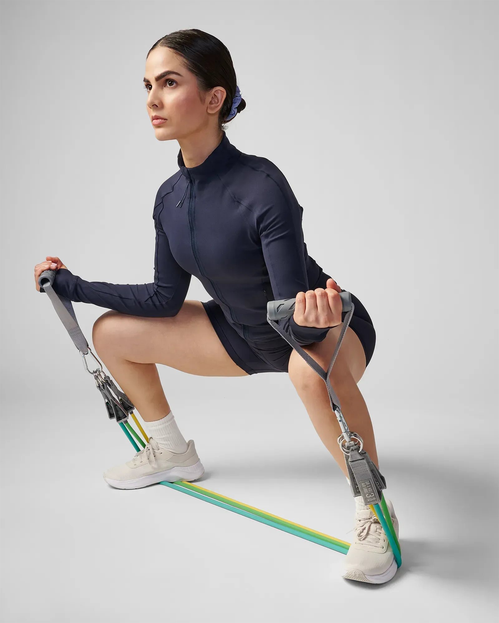 Woman performing a lateral lunge with the EQYP Power 3 Strength Kit handles and stacked resistance tubes underfoot