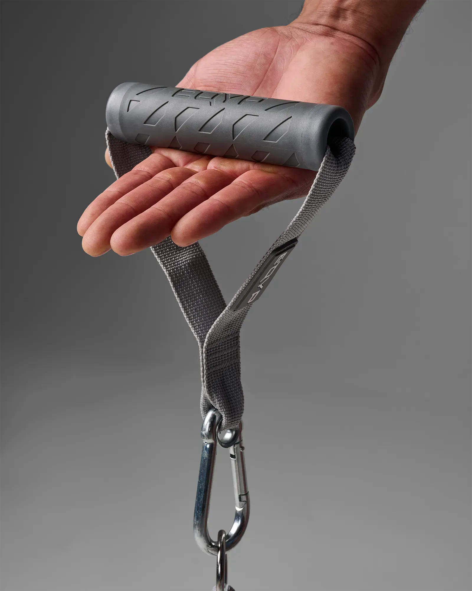Hand holding a single EQYP Power Tubes Handle showing grip texture and carabiner clip