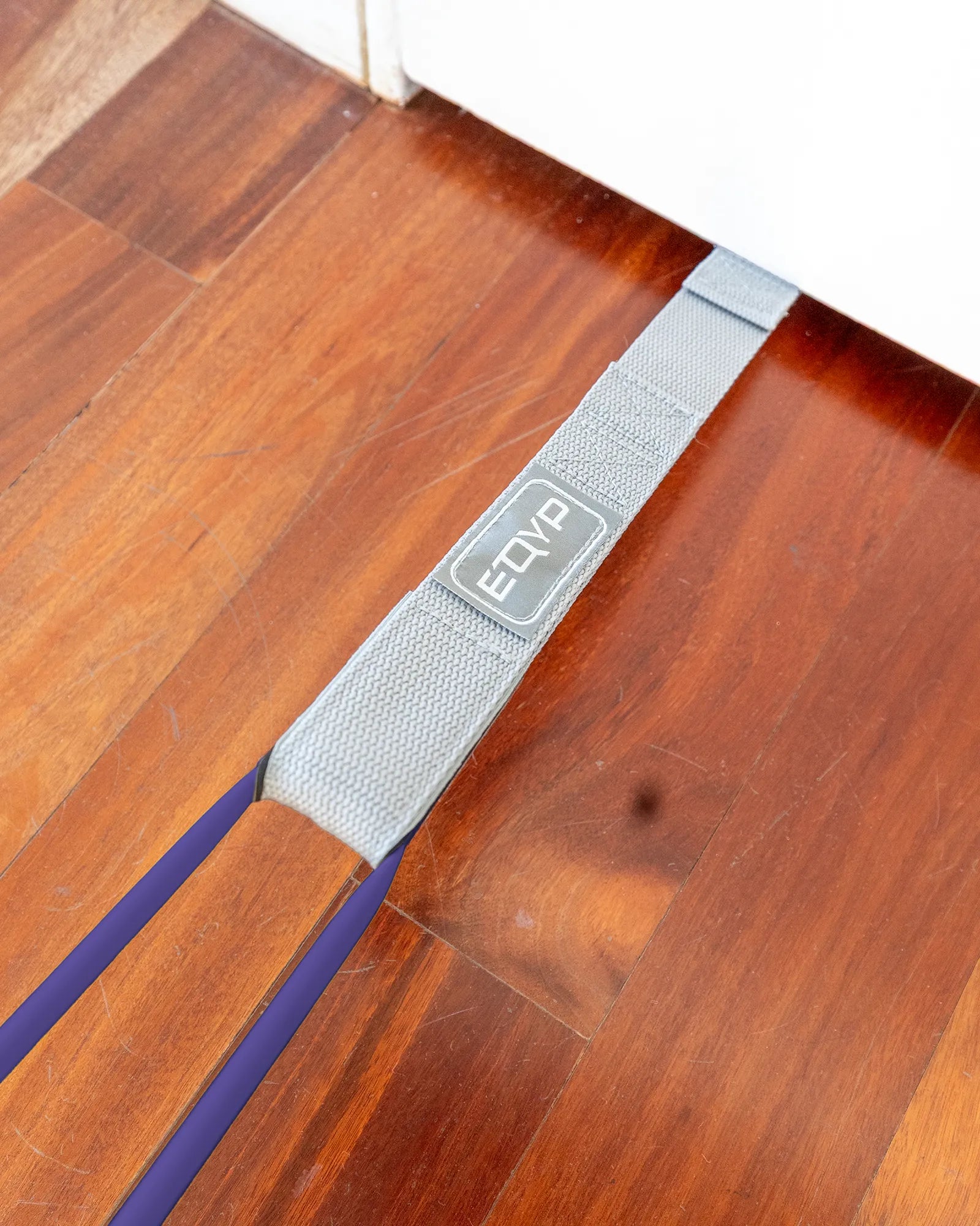 EQYP Power Tubes Door Anchor threaded under a door at floor level with resistance tube attached
